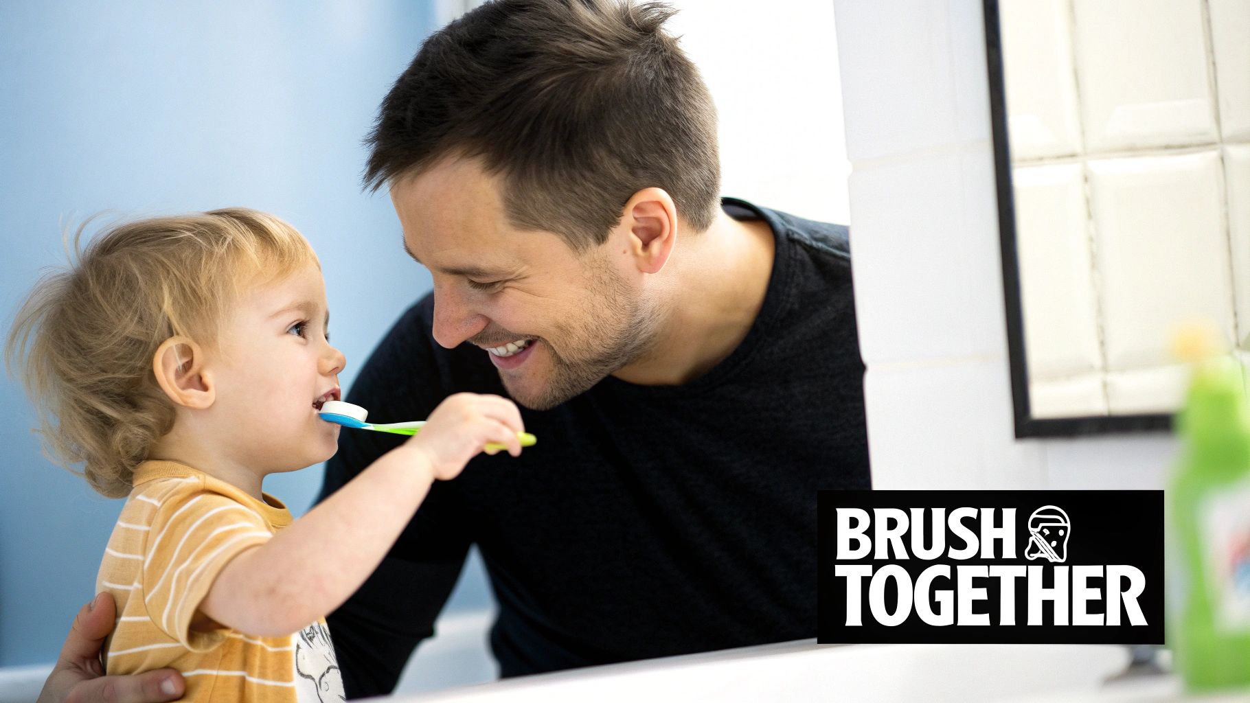 A smiling father and his toddler enthusiastically brush their teeth together in a bright bathroom.