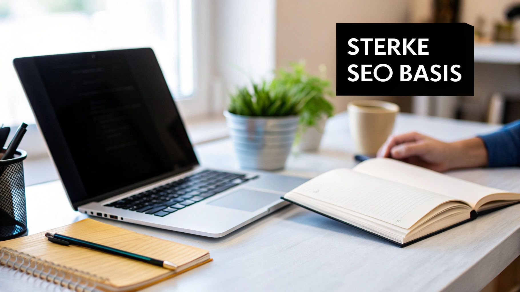 Een nette werkplek met laptop, notitieboek, koffie, plant en een hand. Sterke SEO basis.