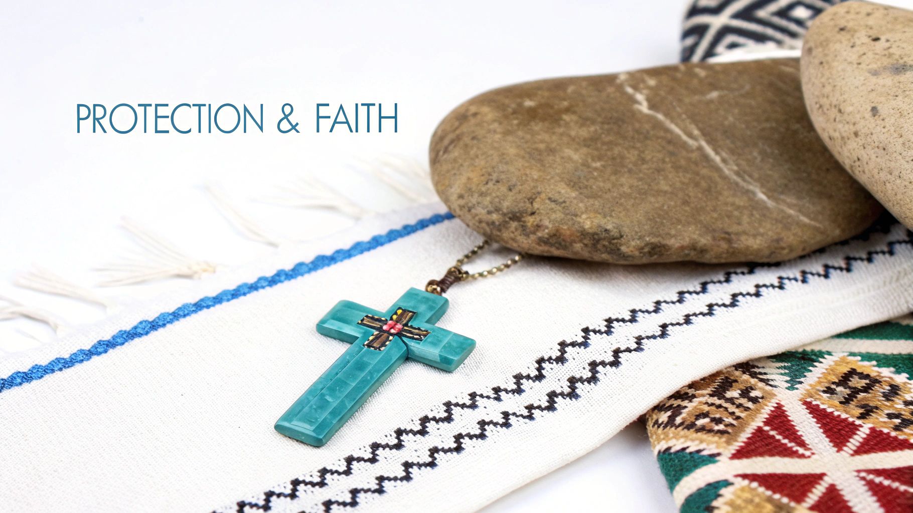 A turquoise cross necklace with intricate details rests on a white patterned fabric next to two stones.