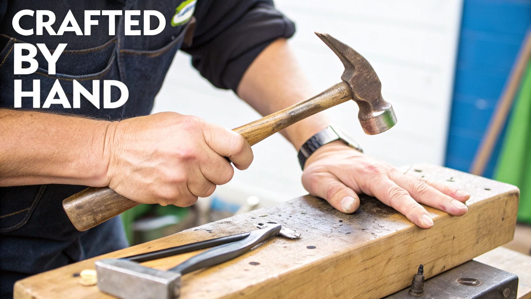 A person's hands using a hammer to craft an item on a wooden block, text reads 'CRAFTED BY HAND'.