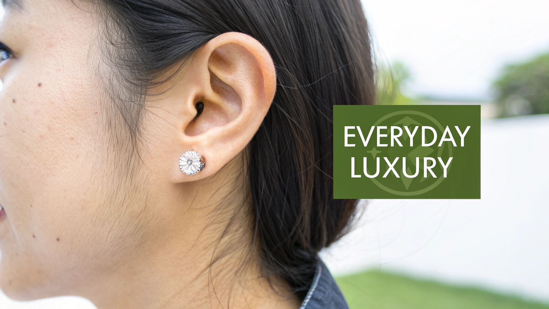 A close-up of a woman's ear featuring a sparkling, circular flat-back moissanite earring.