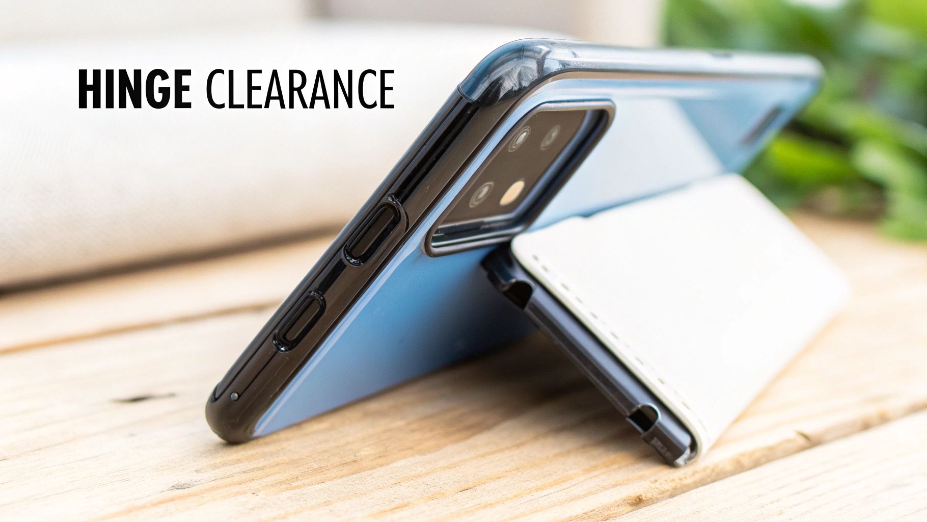 A blue smartphone in a black case uses a white folio stand on a wooden table, emphasizing case design and clearance.