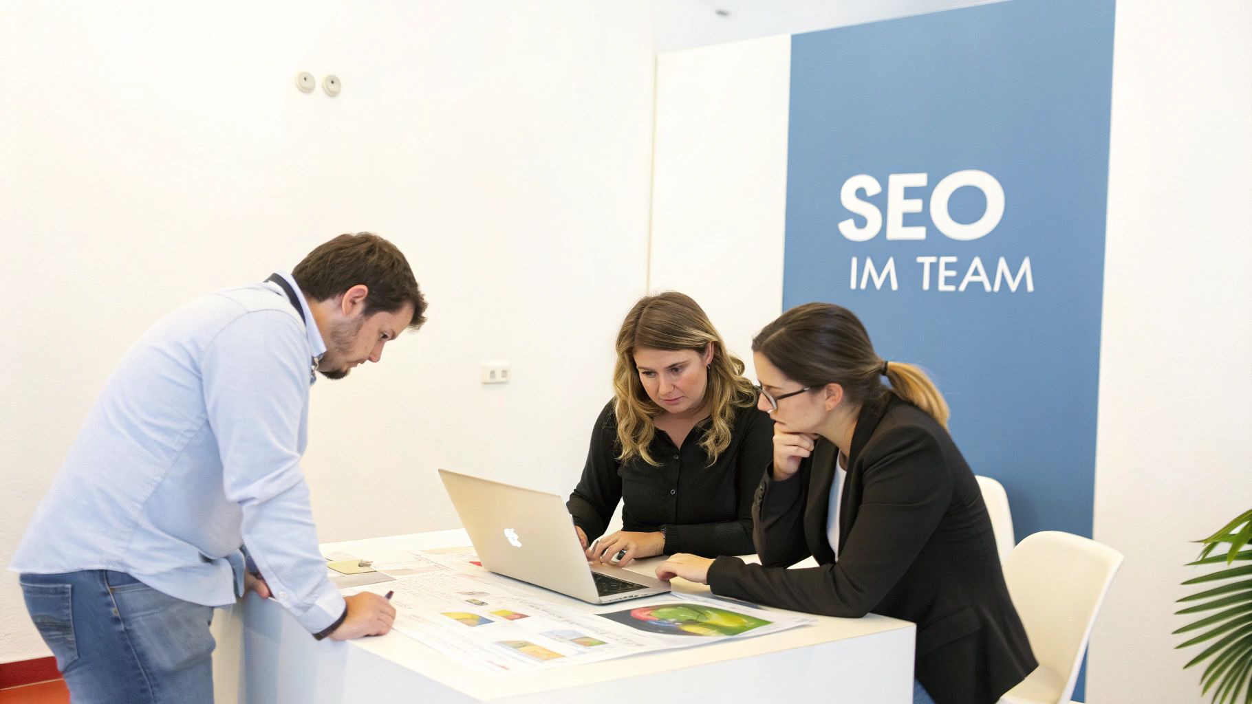 Ein Team arbeitet gemeinsam an einem Laptop in einer hellen, modernen Büroumgebung, was die kollaborative Natur eines SEO Workshops symbolisiert.