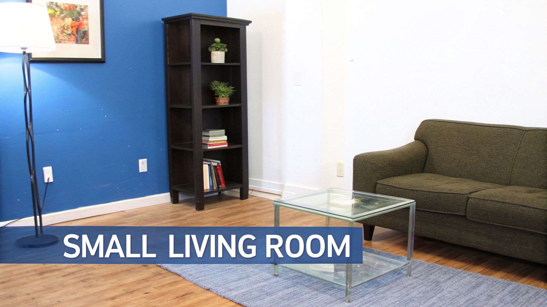 A compact living room featuring a green sofa, tall bookshelf, glass coffee table, and blue accent wall.