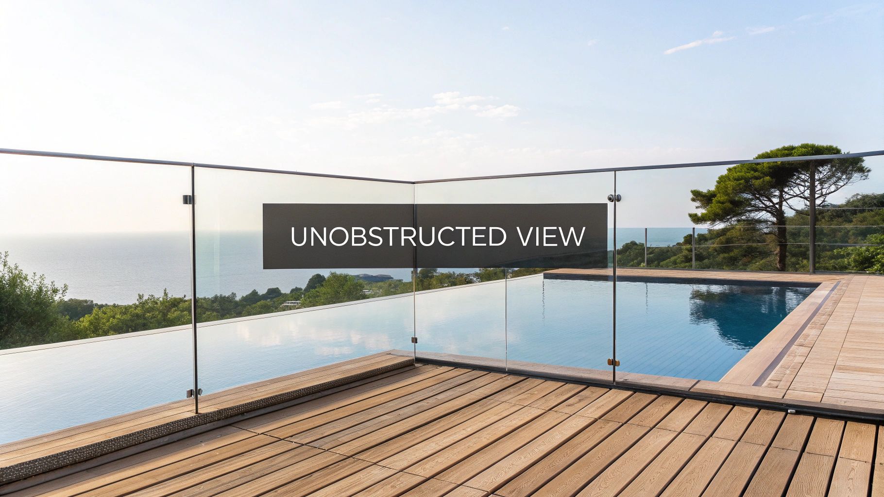 A modern infinity pool with a clear glass railing providing an unobstructed ocean view and surrounding green landscape.
