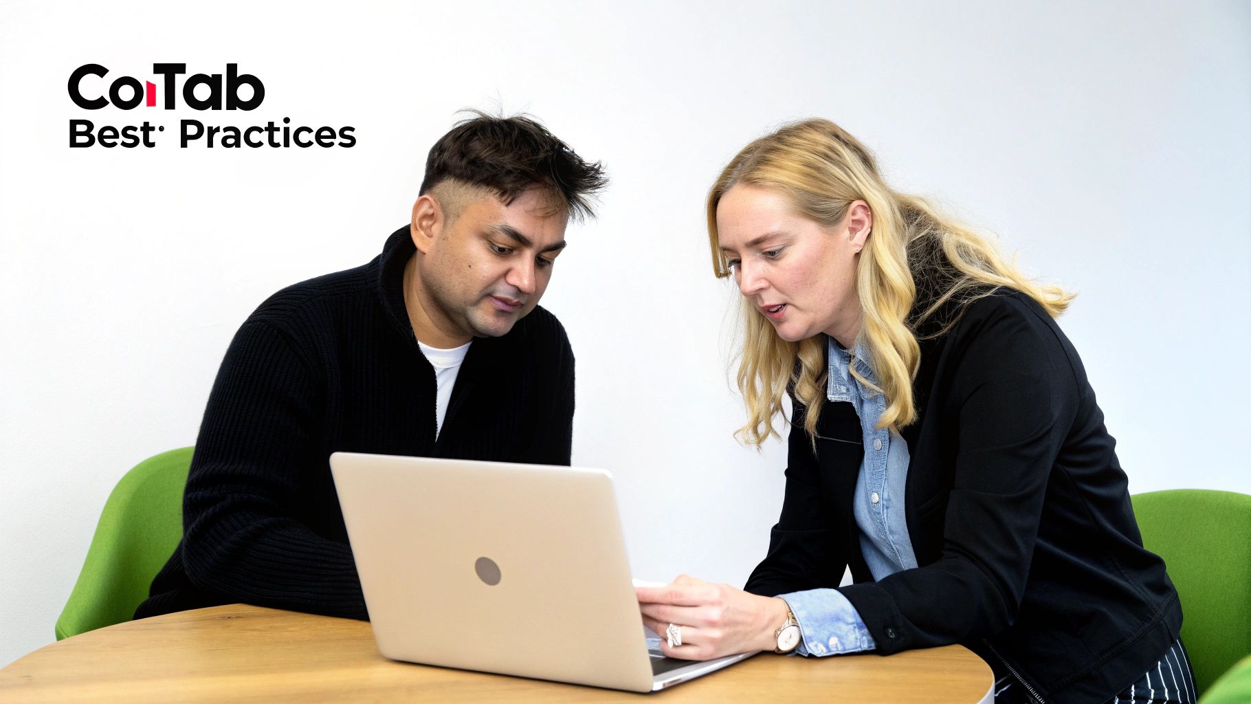 Two professionals, a man and a woman, collaborate on a laptop at a table.