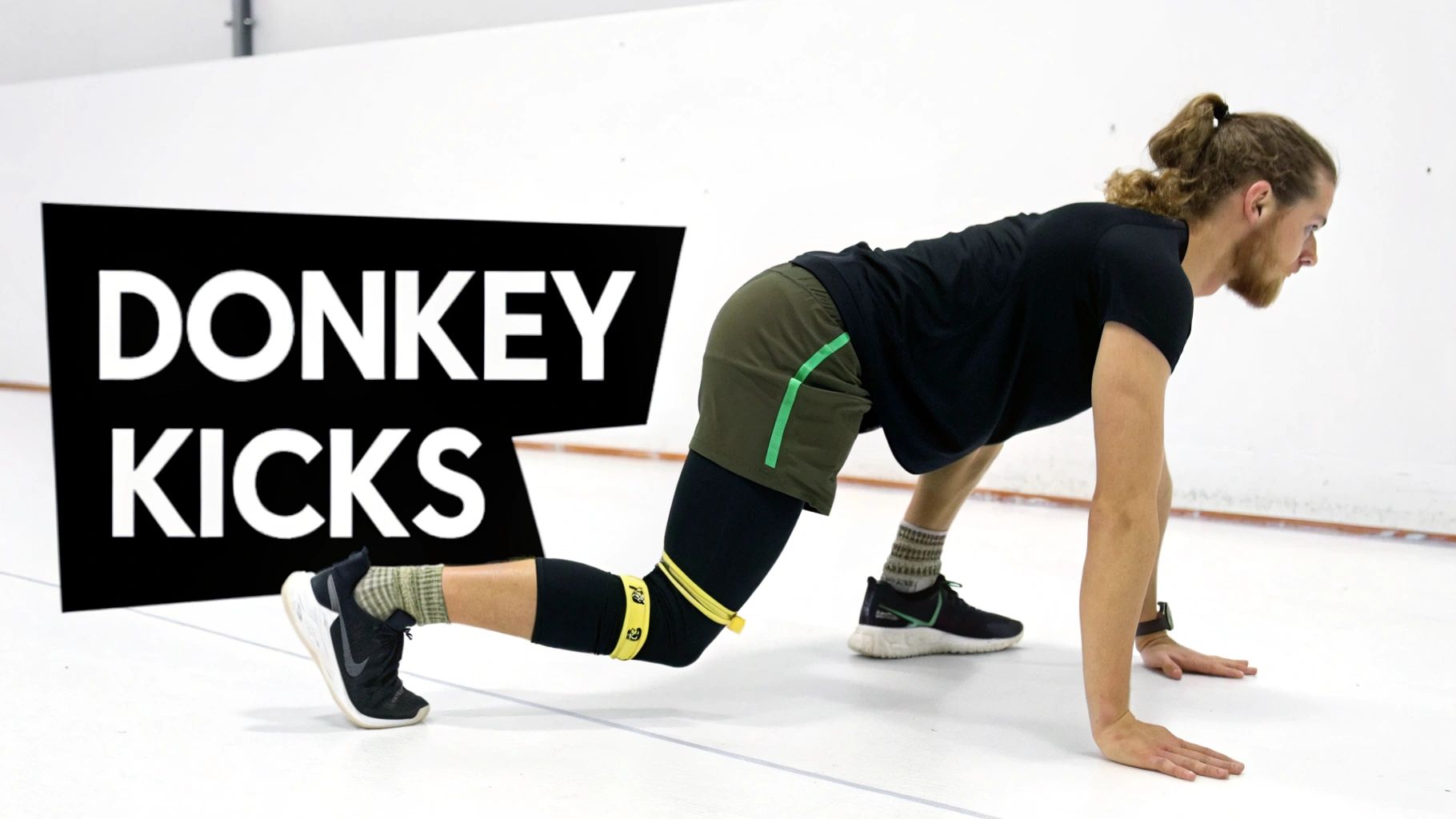 Woman performing donkey kicks exercise with resistance band in gym studio for glute activation