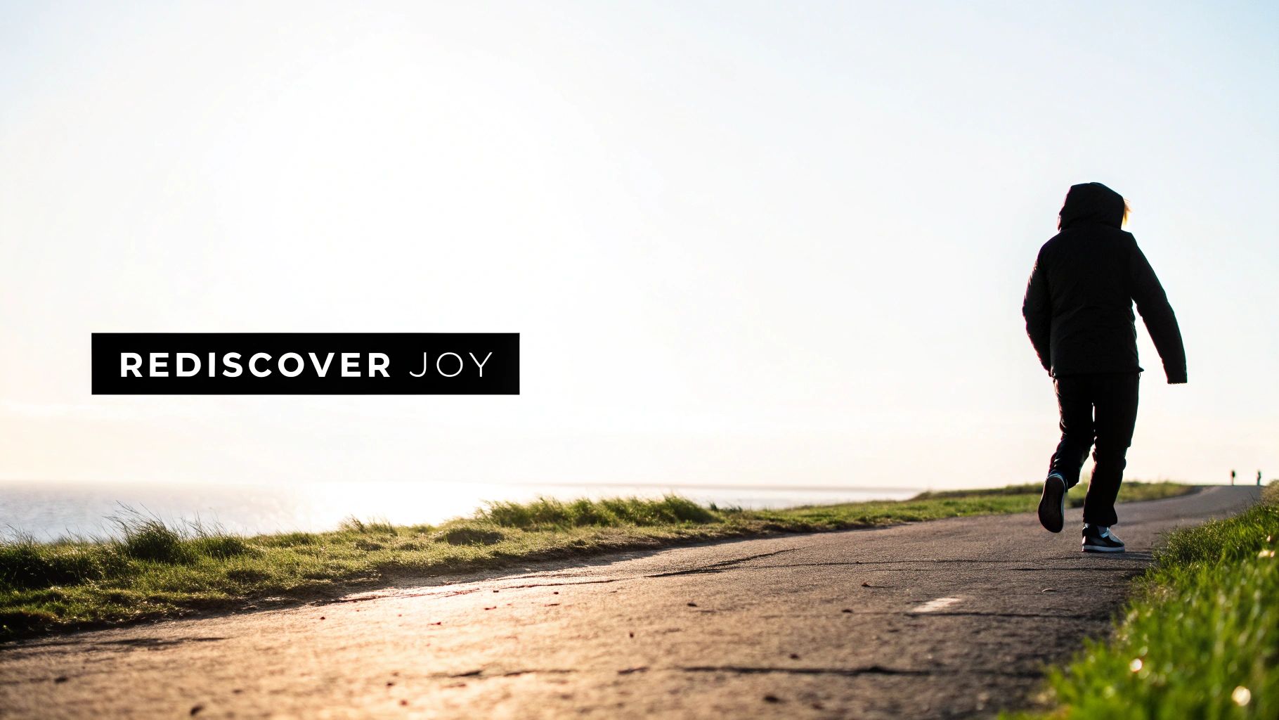 A person walks on a scenic path by the ocean at sunset, with text 'REDISCOVER JOY'.