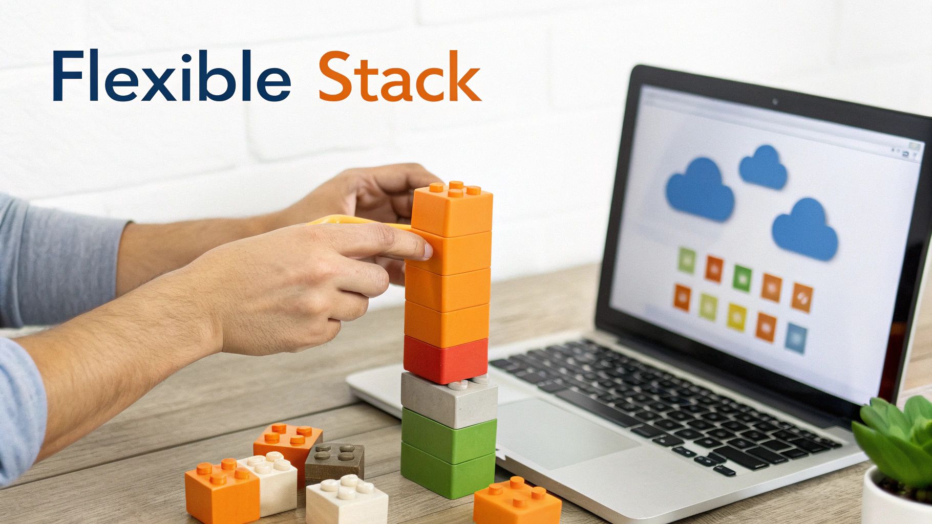 A person's hands stack colorful building blocks on a desk next to a laptop displaying cloud software icons.