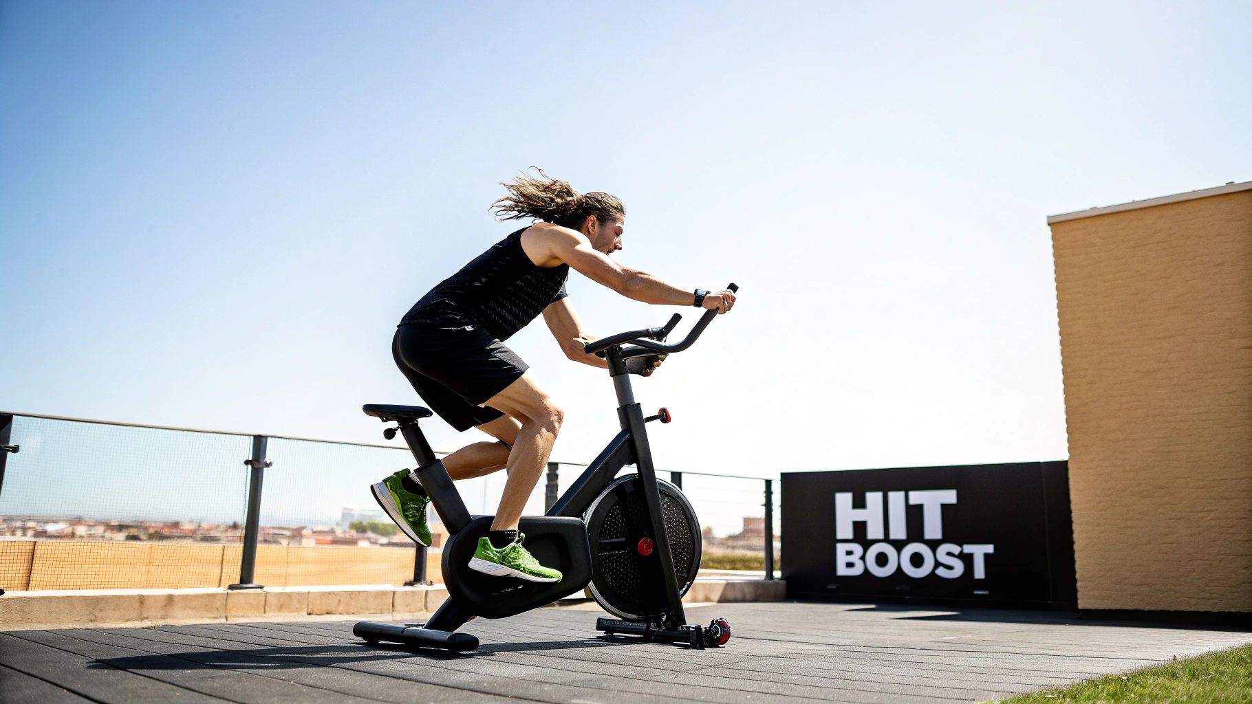 A man with long hair vigorously exercising on a stationary bike outdoors, with a "HIT BOOST" sign.