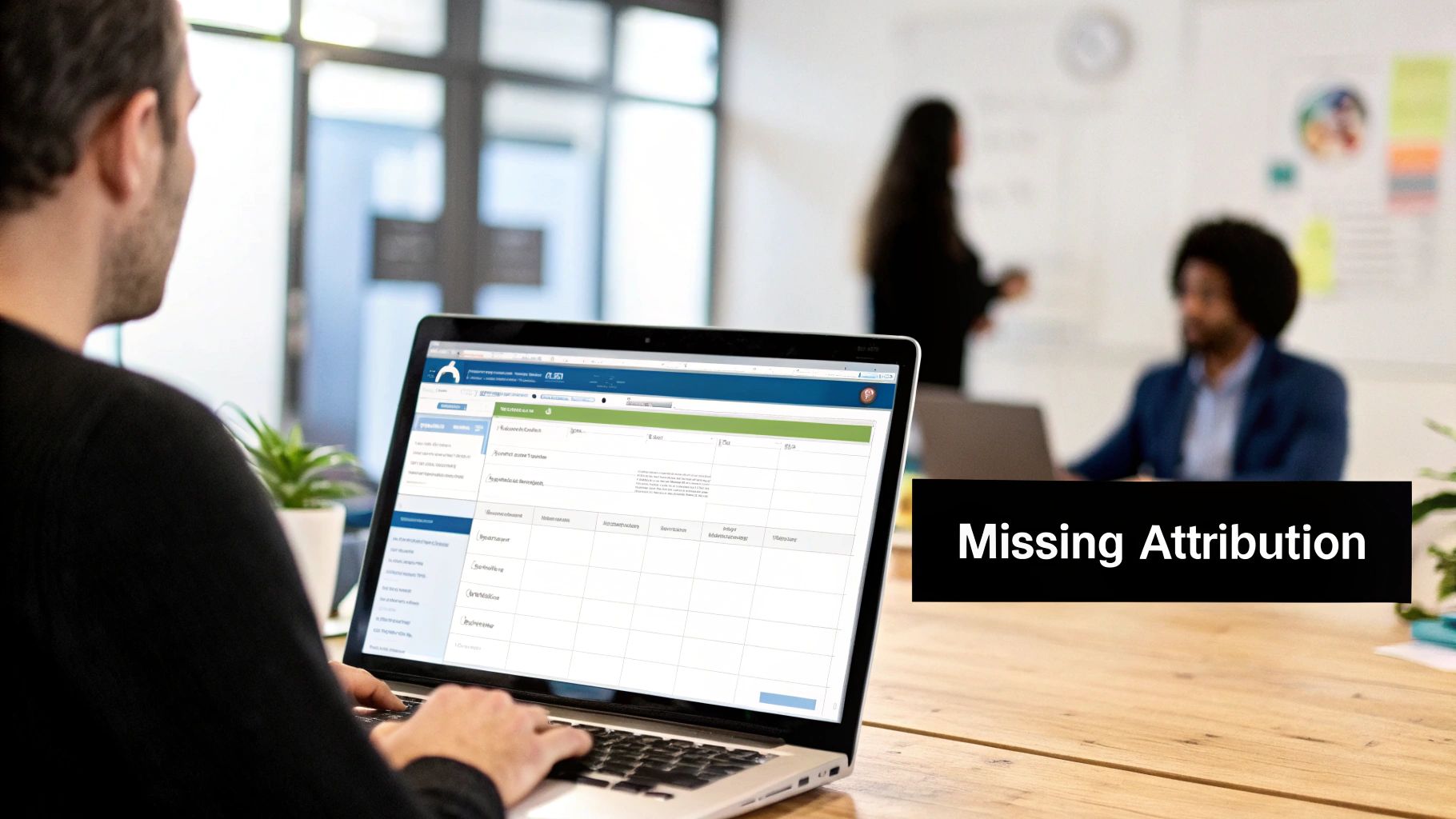 A person from behind is typing on a laptop displaying data in an office environment.