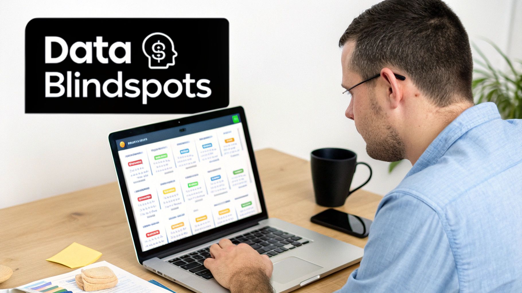 A man in a blue shirt works on a laptop displaying data, next to a 'Data Blindspots' sign.