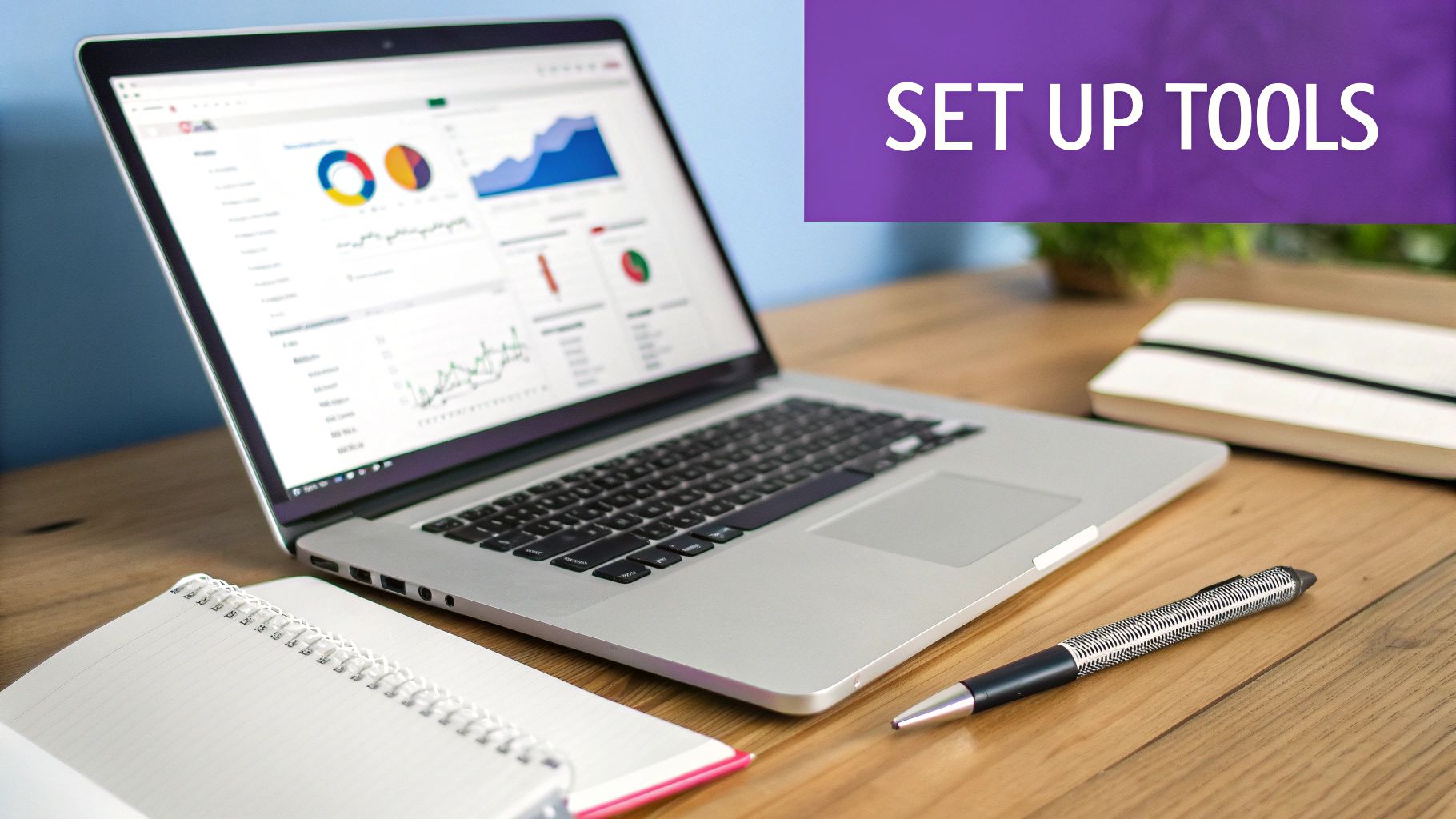 A laptop displaying data charts on a wooden desk with a notebook, pen, and 'SET UP TOOLS' banner.