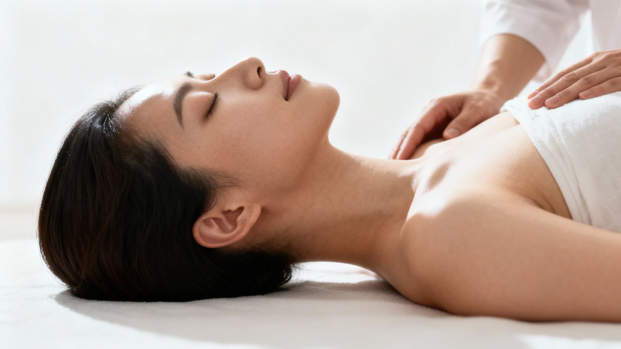 A serene young woman receiving a relaxing neck and shoulder massage from a therapist.