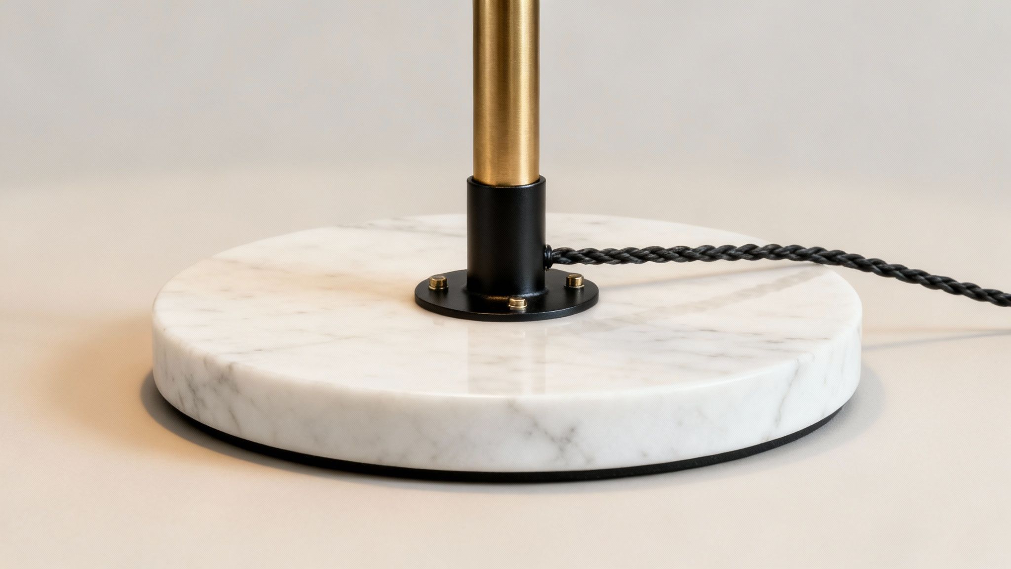Modern lamp base featuring a round white marble slab, black stand, and braided power cord.