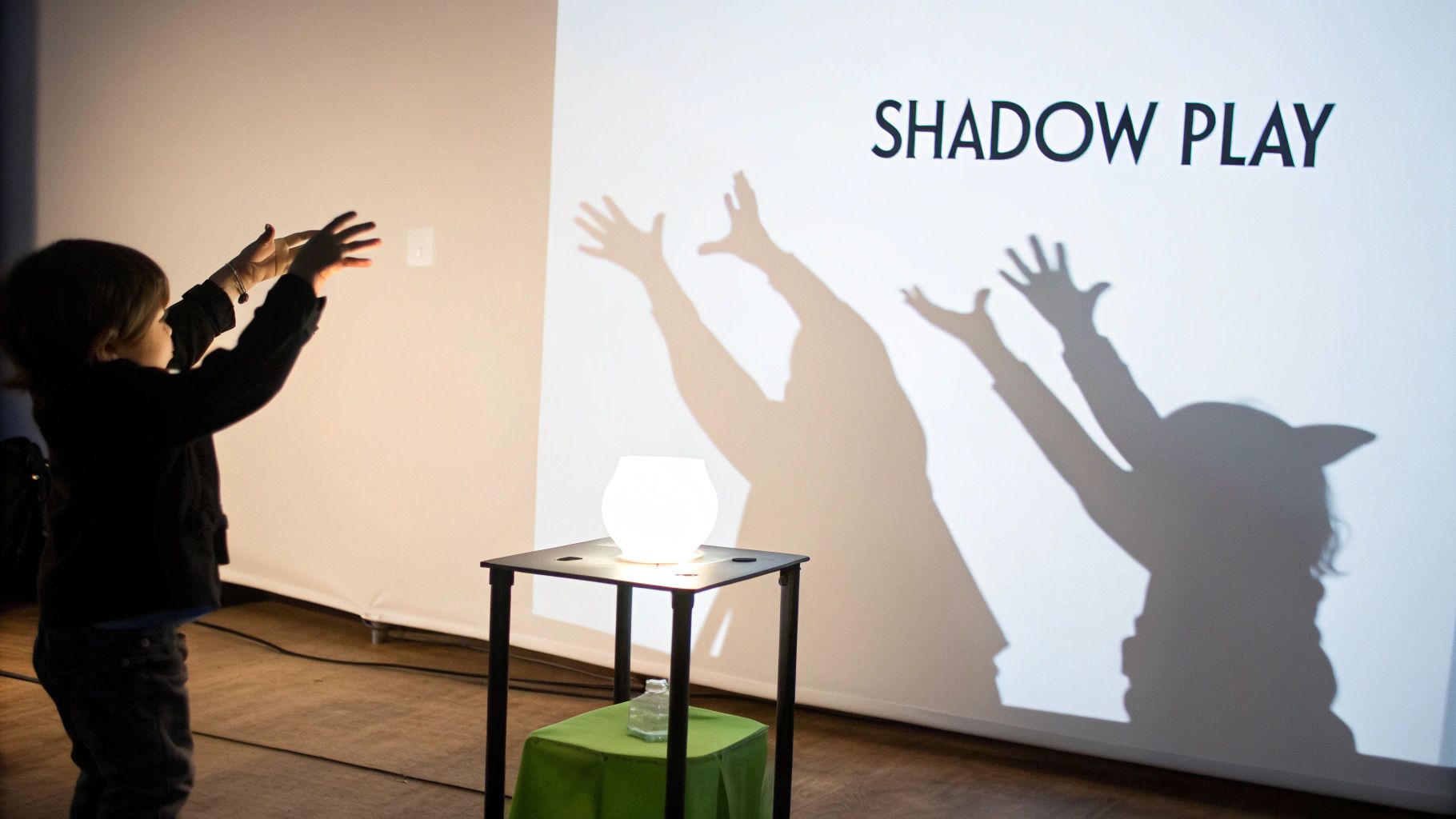 A child creates shadows on a projection screen that reads 'SHADOW PLAY', an engaging sensory activity.