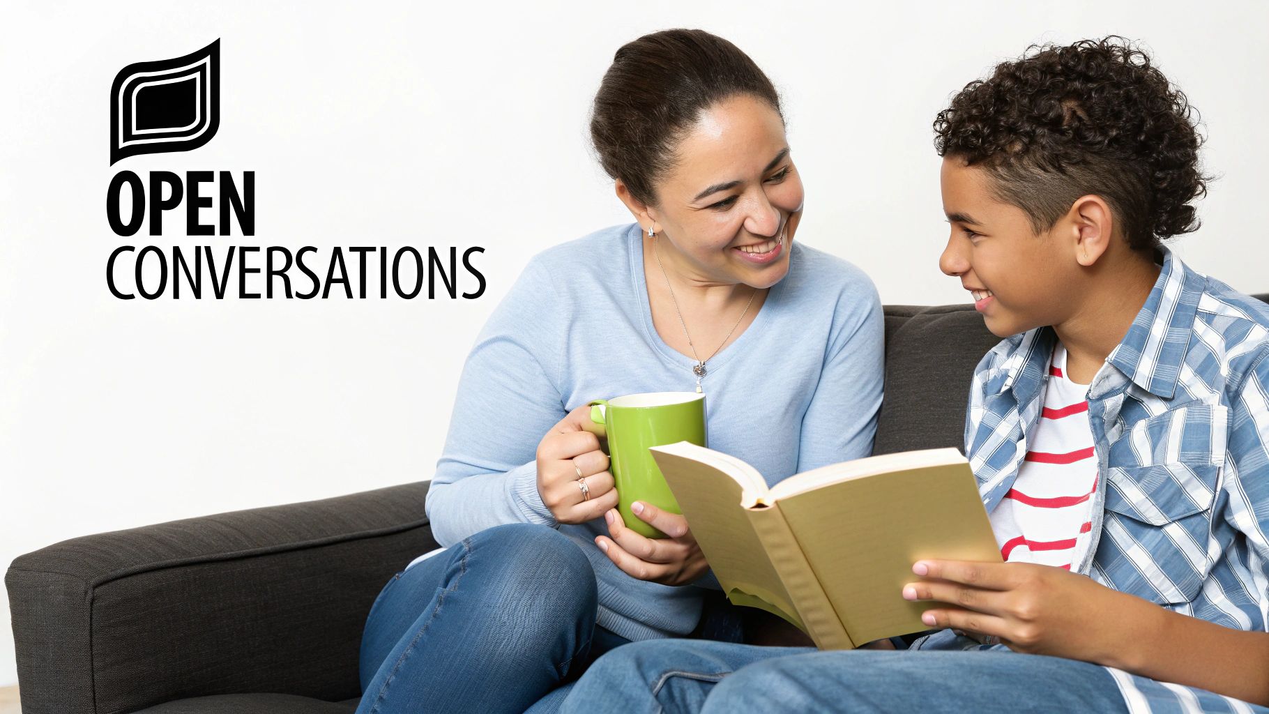 A happy mother and son share a book and conversation on a couch, enjoying time together.