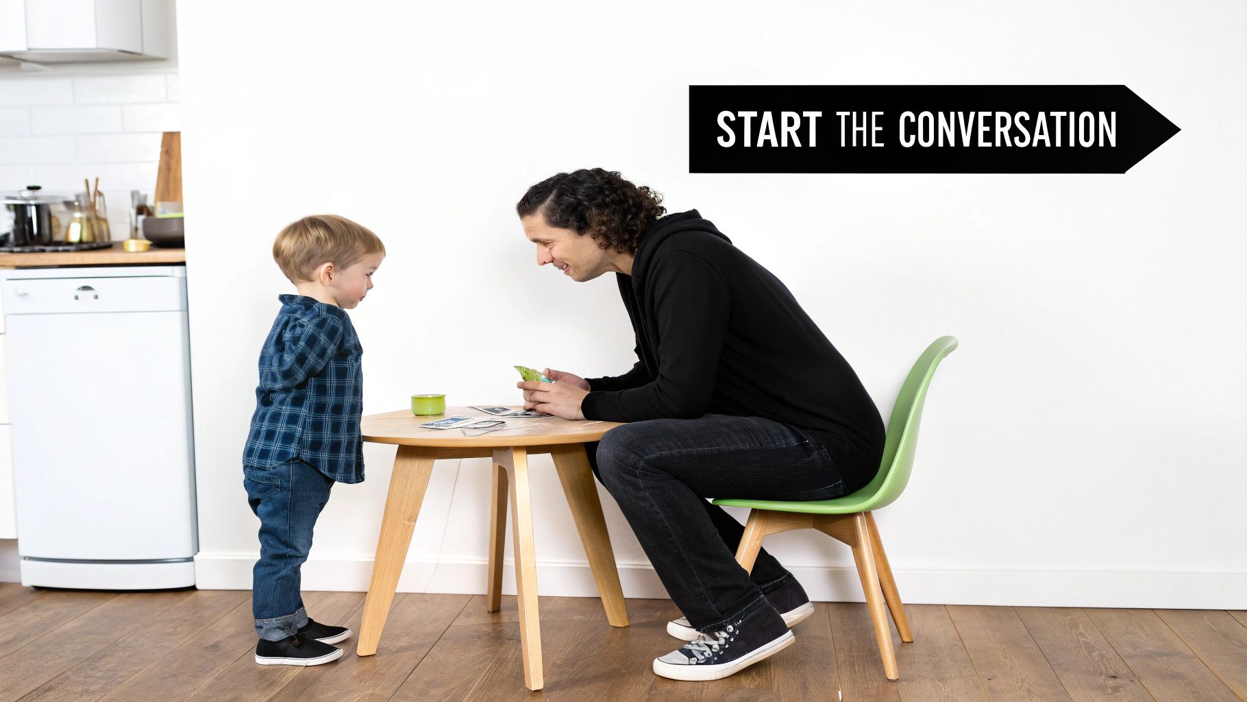 A man and a young child playing a card game at a table in a bright room.
