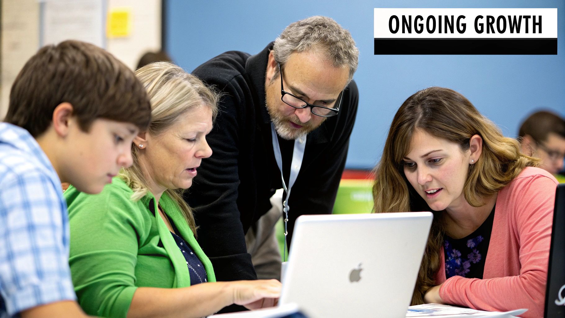 A group of educators collaborating around a table with laptops and notes.