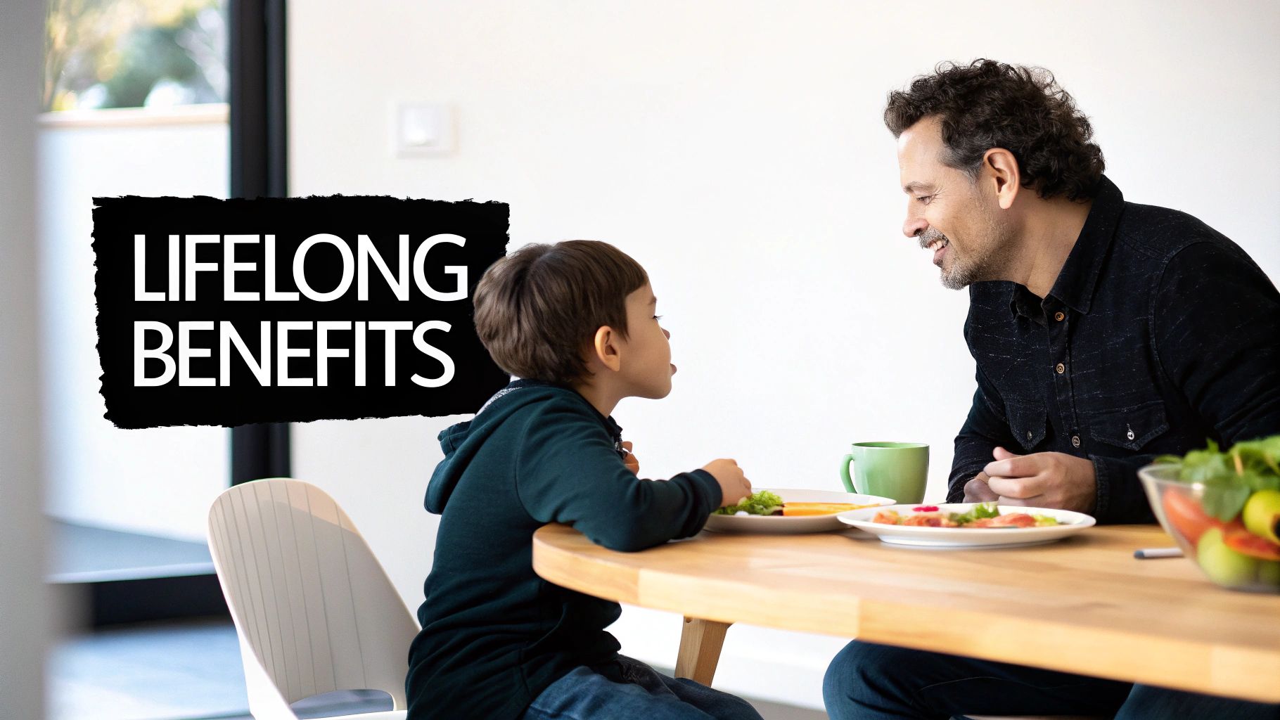 A smiling father and son share a happy meal and conversation at a bright table.