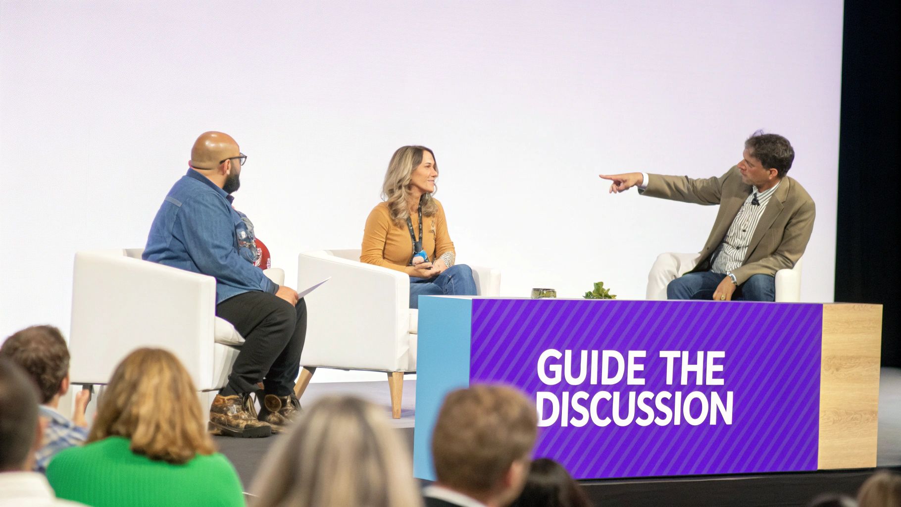 A moderator confidently leading a panel discussion on stage, with engaged panelists listening.