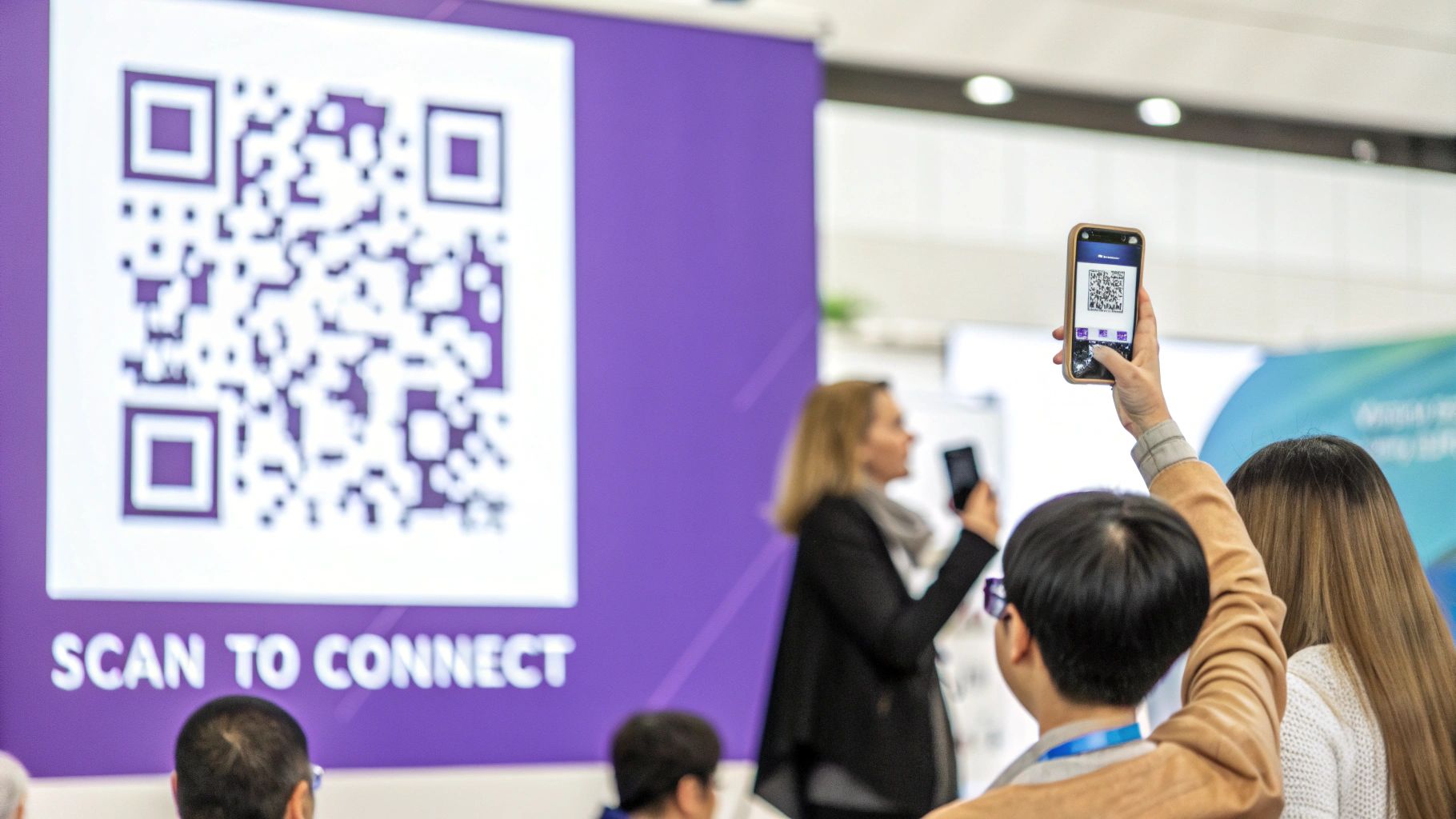 Attendees at a trade show scanning a large QR code on a purple banner with their smartphones.