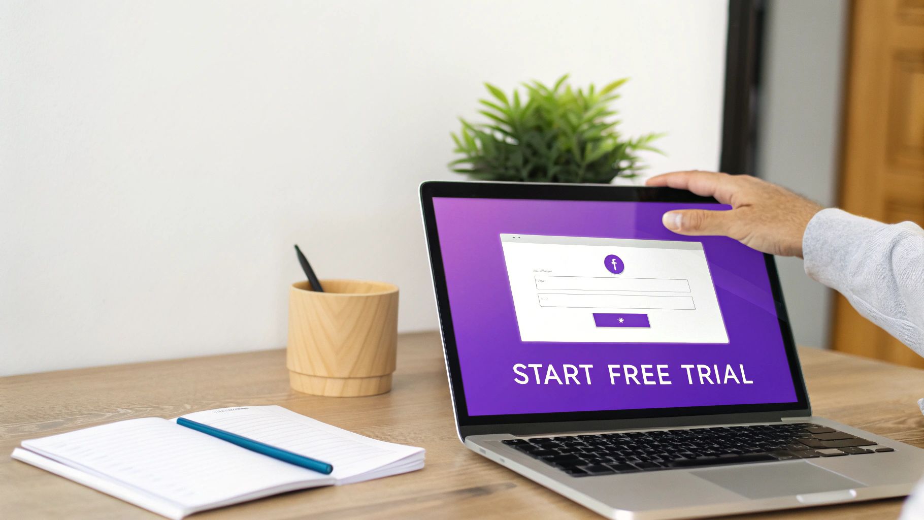 A person's hand interacting with a laptop showing a 'Start Free Trial' page.