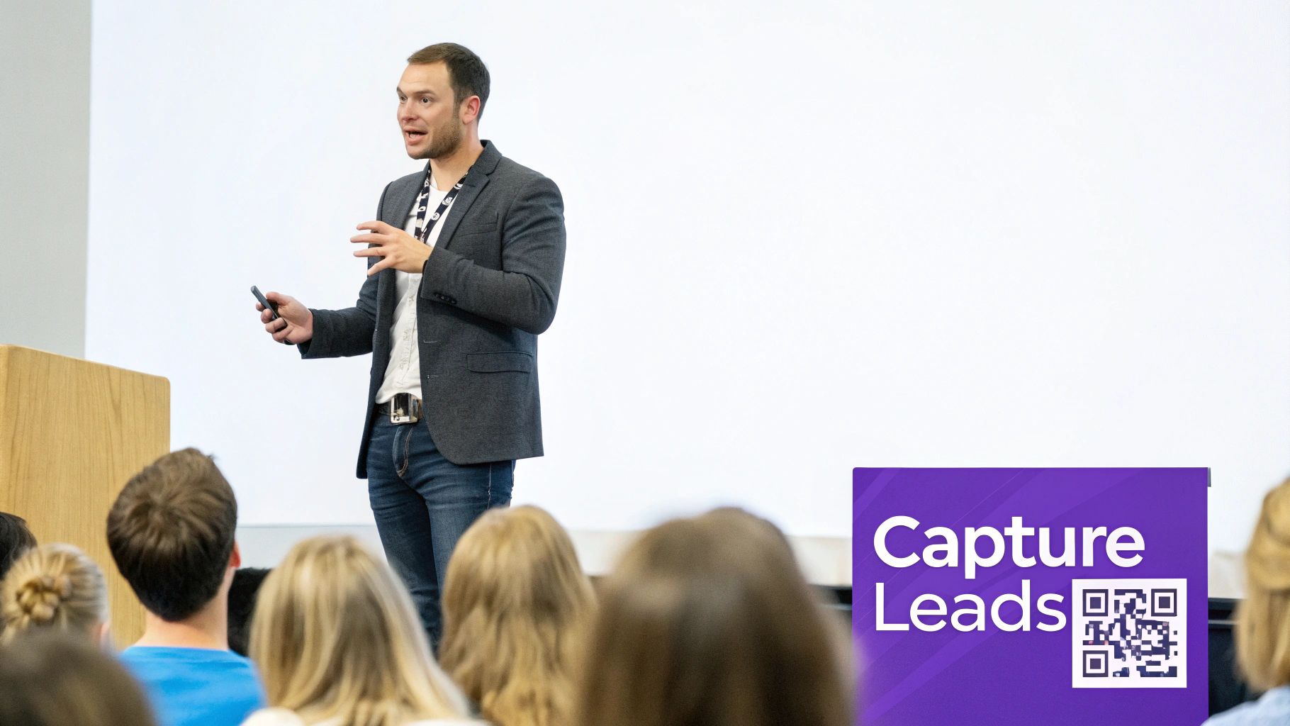 Professional speaker presenting to an audience with a "Capture Leads" sign and QR code on display.