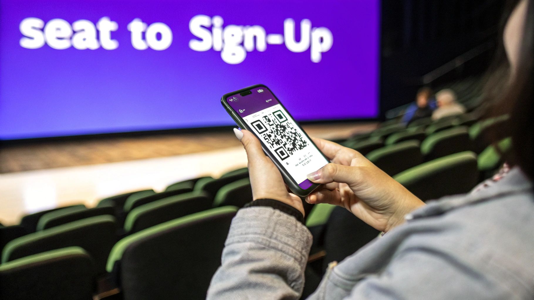 A person using a smartphone to scan a QR code at an event with a screen displaying text.
