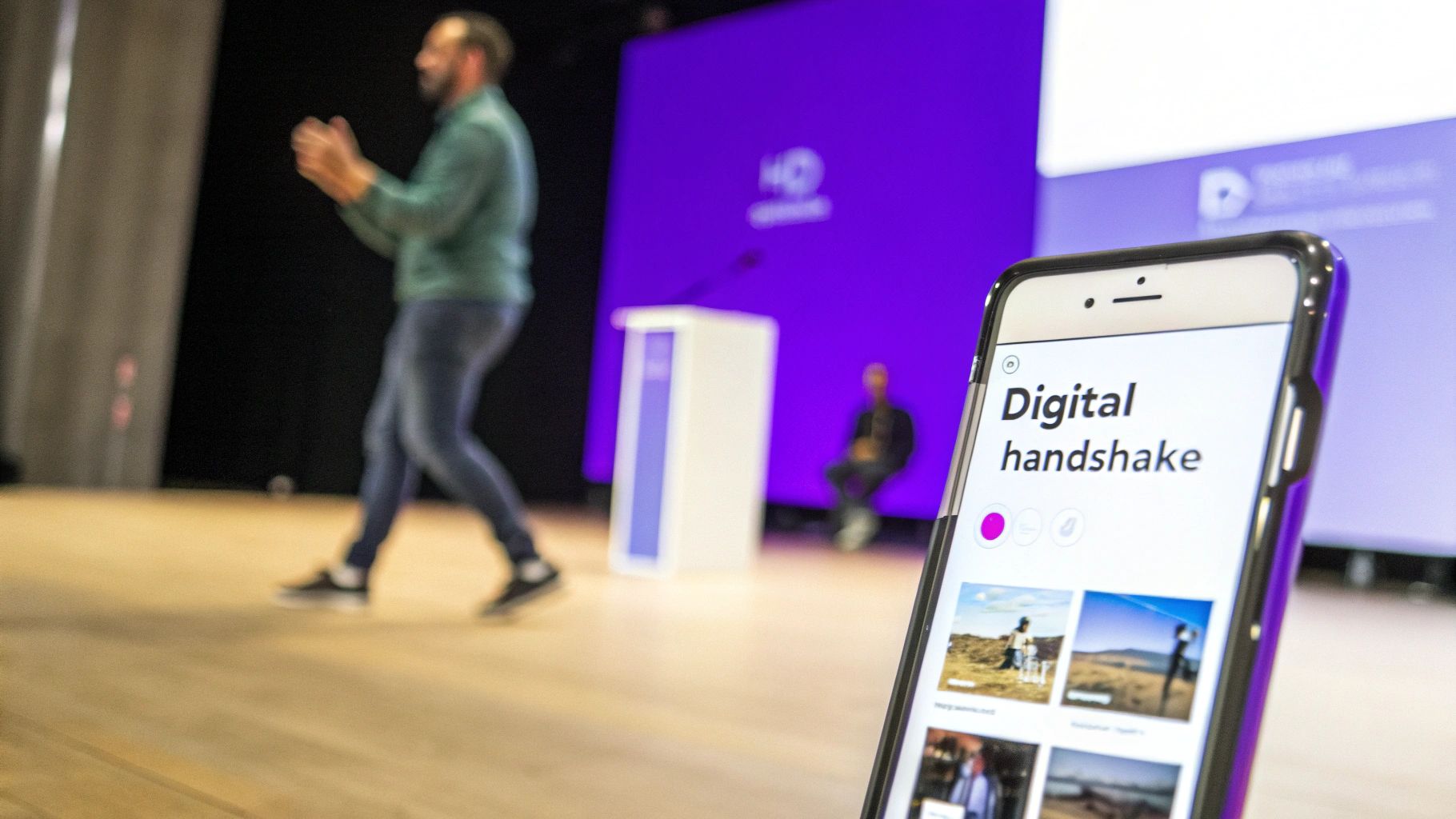 Close-up of a smartphone displaying 'Digital handshake' app during a conference presentation.