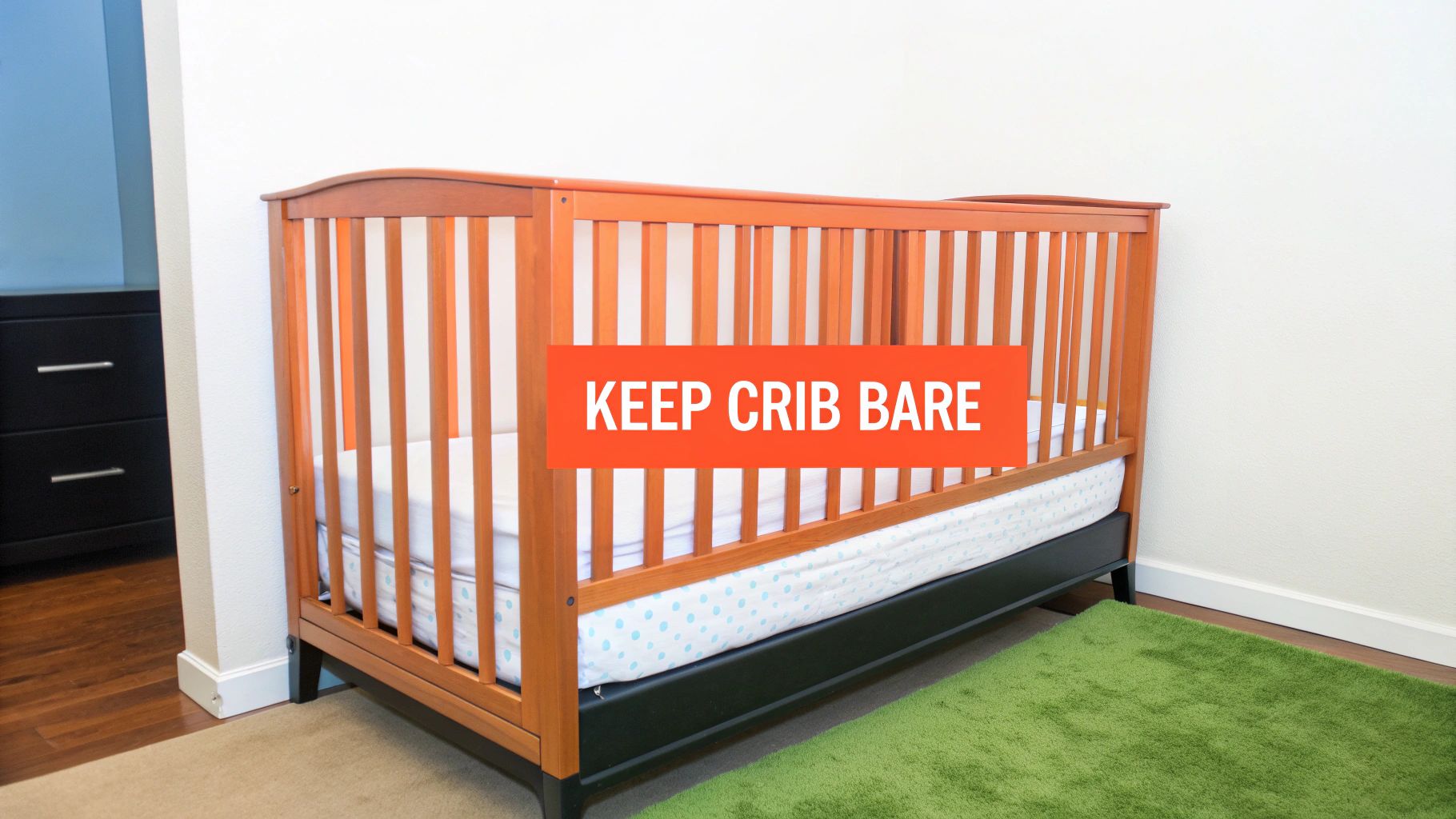 A wooden baby crib with a white mattress and a light blue polka dot sheet, featuring an orange banner with the text 'KEEP CRIB BARE' for safe sleep awareness. A green rug is on the floor.