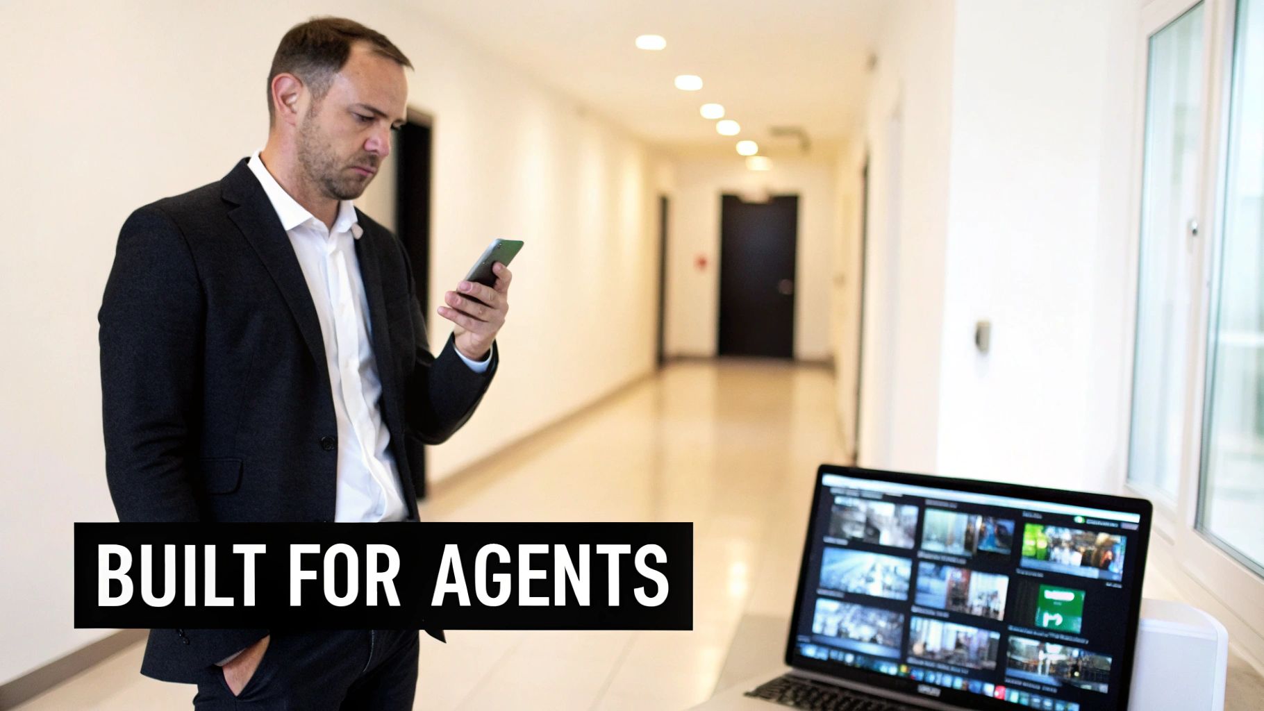 A professional real estate agent uses a phone and laptop displaying multiple video feeds, indicating property management.