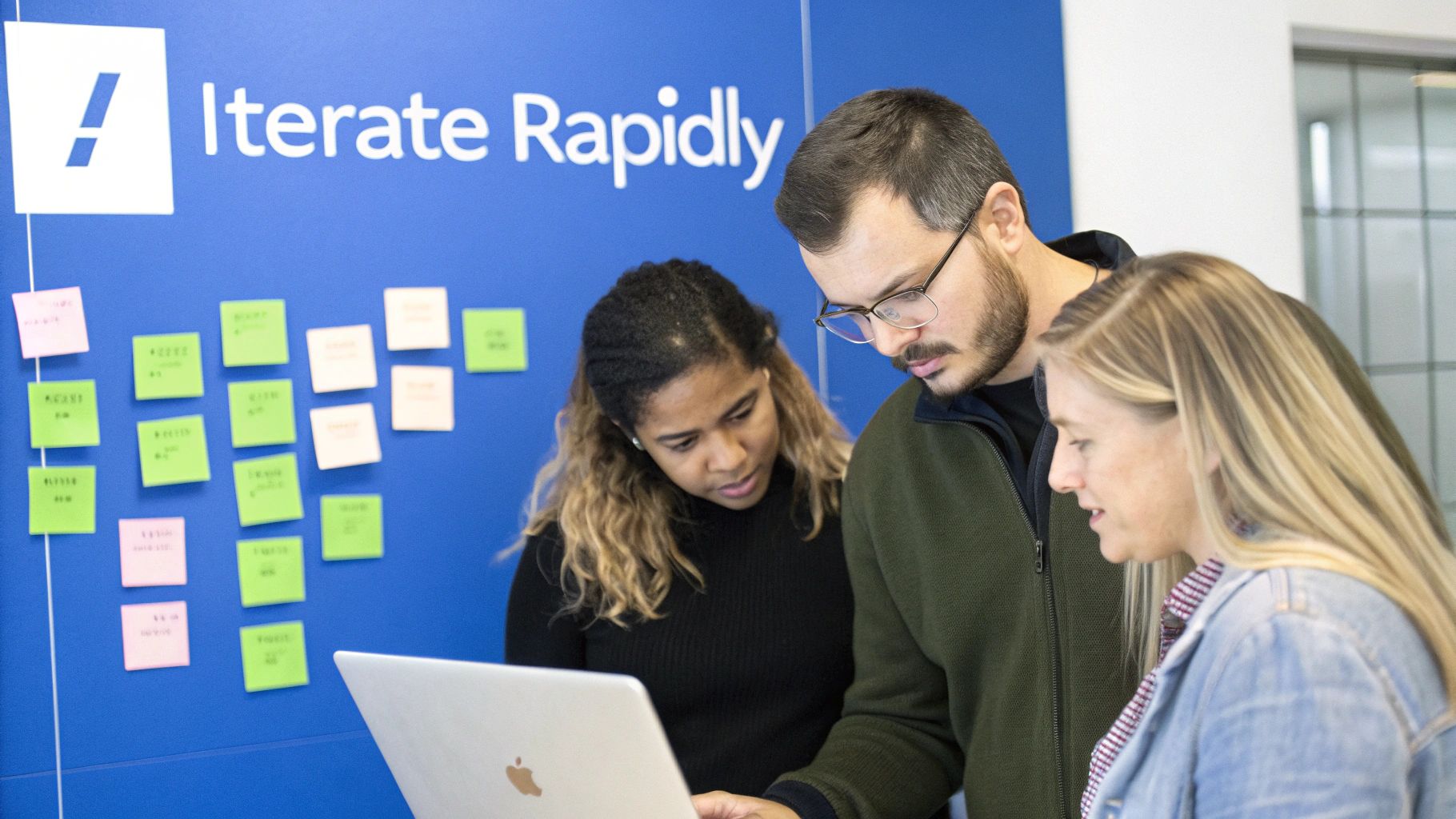 Three diverse colleagues collaborate on a laptop in a modern office with sticky notes.