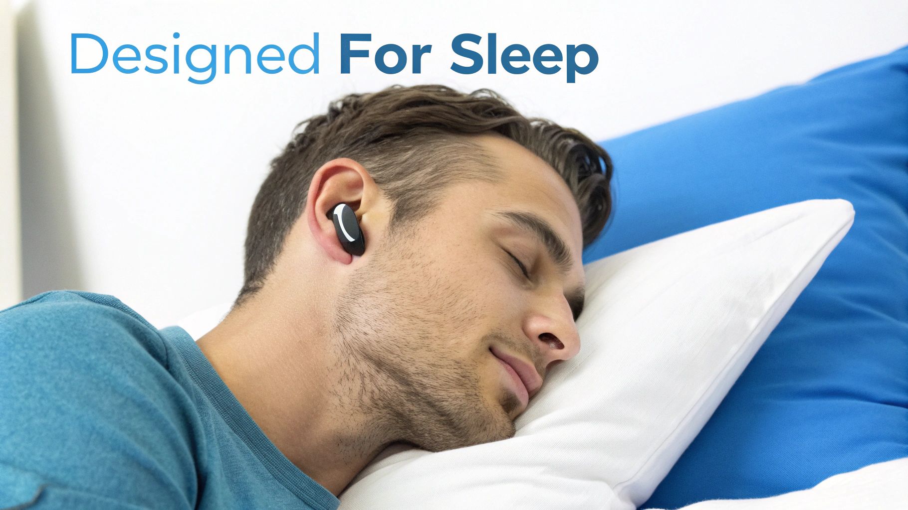 A man is sleeping soundly on a white pillow, wearing a black earbud in his ear, highlighting its use for sleep.