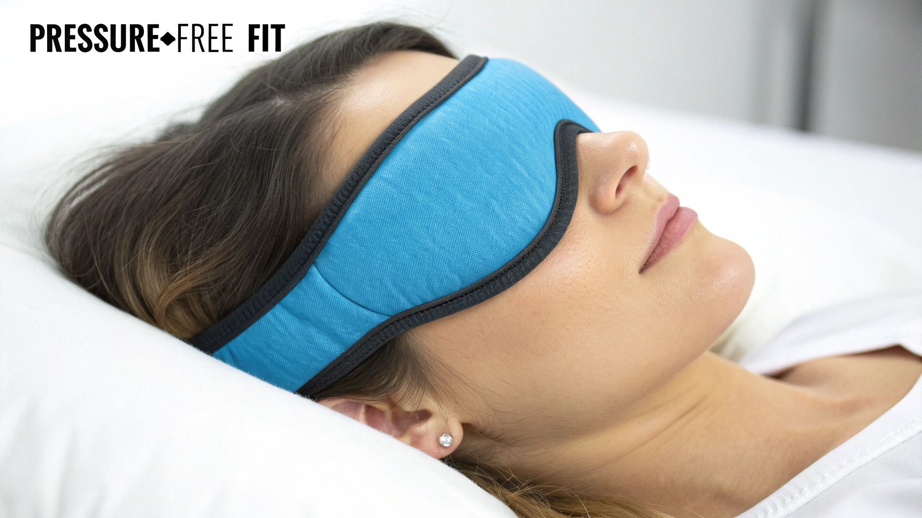 A woman sleeps soundly on a white pillow, wearing a comfortable blue sleep mask.