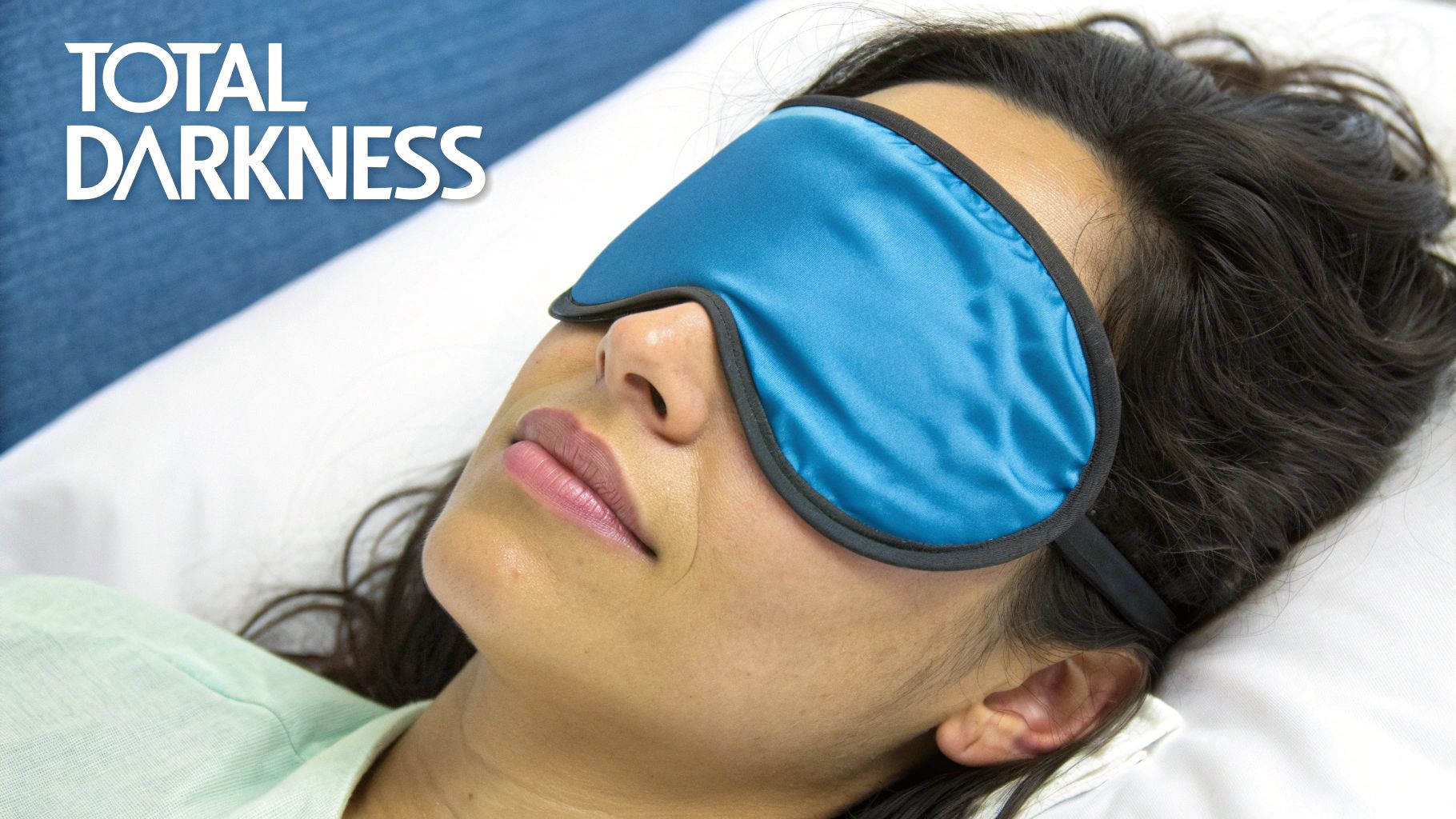 A person sleeping peacefully in bed with a blue satin eye mask covering their eyes.