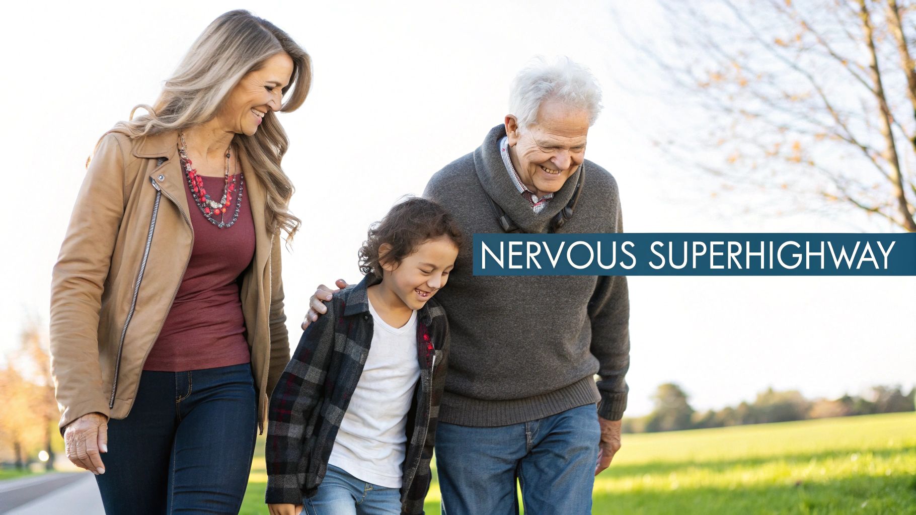 A happy multi-generational family, including grandparents and a child, smiling and walking in a park.