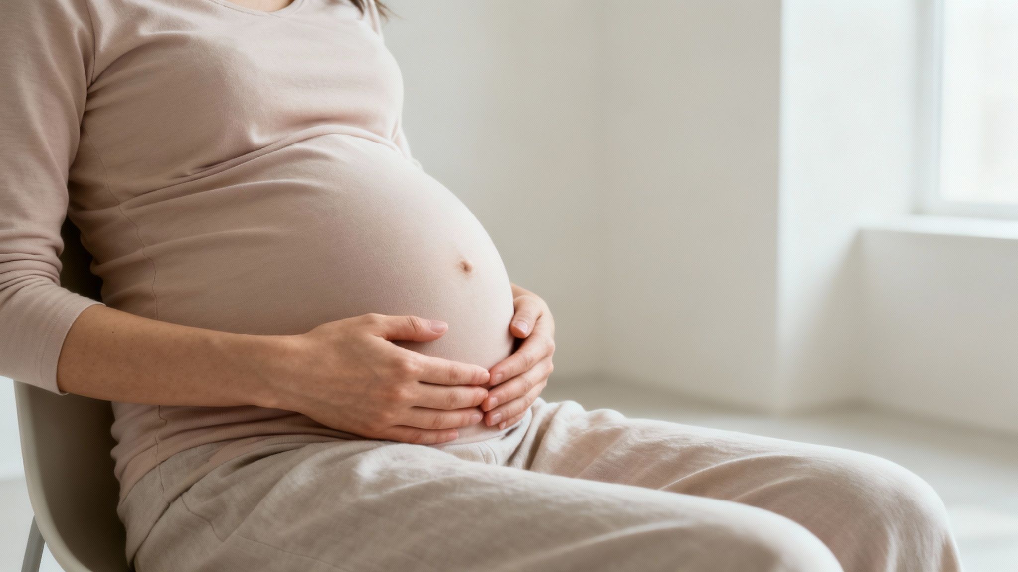Femme enceinte au premier trimestre se tenant le bas-ventre avec une expression pensive