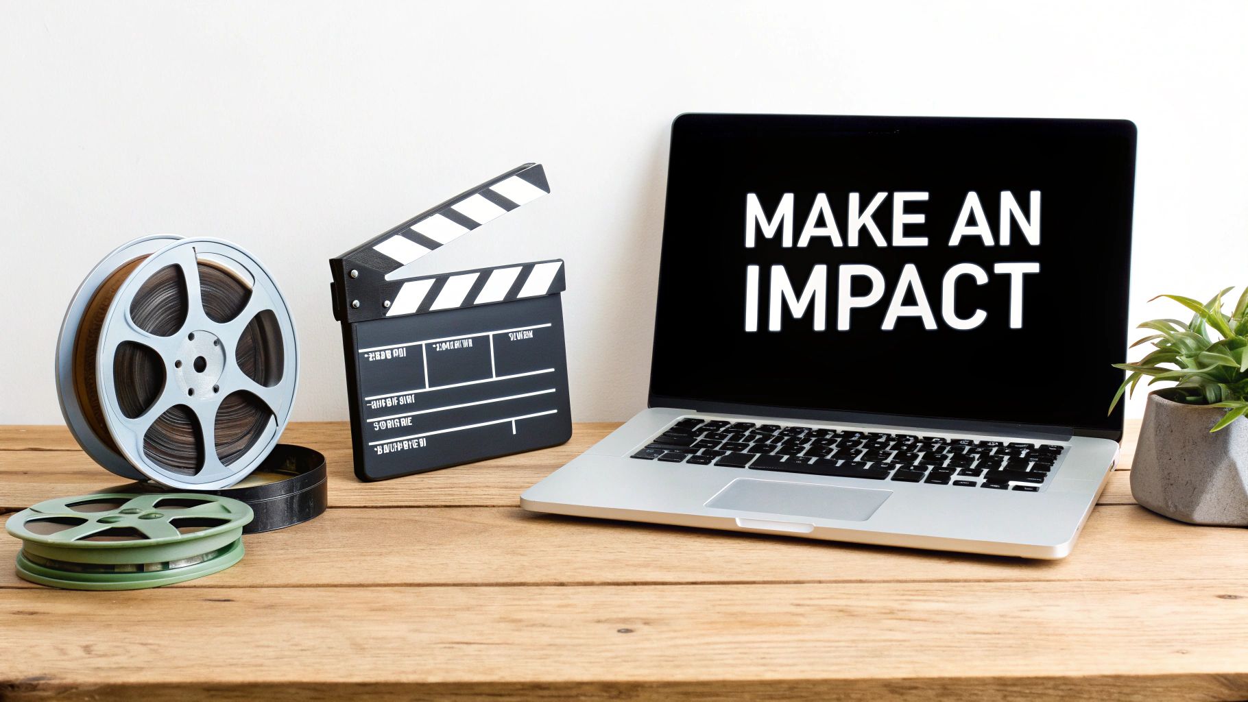 Laptop displaying make an impact message with film reels and clapperboard on wooden desk