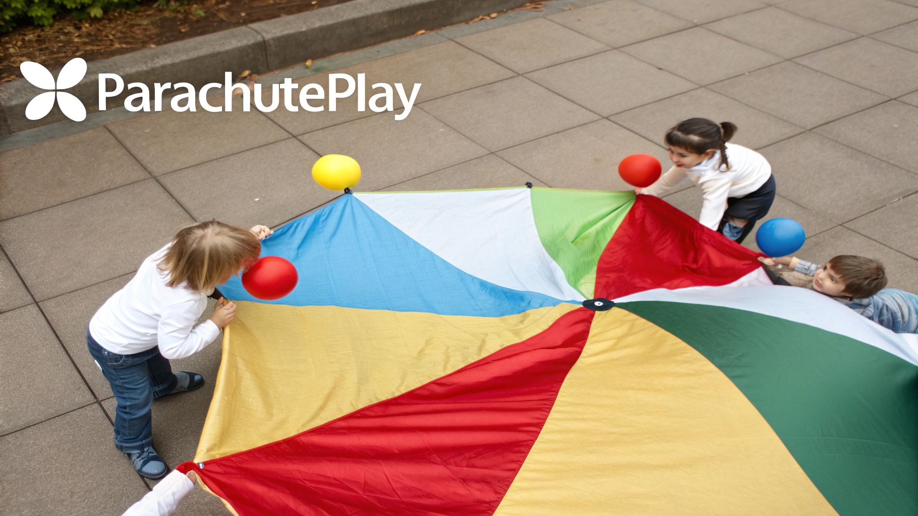 Three young children engage in cooperative play, holding a colorful parachute with balloons on a sunny outdoor day.