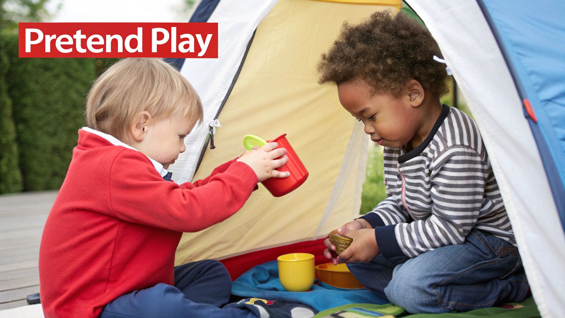 Two young multi-ethnic children engaging in pretend play inside a colorful tent.