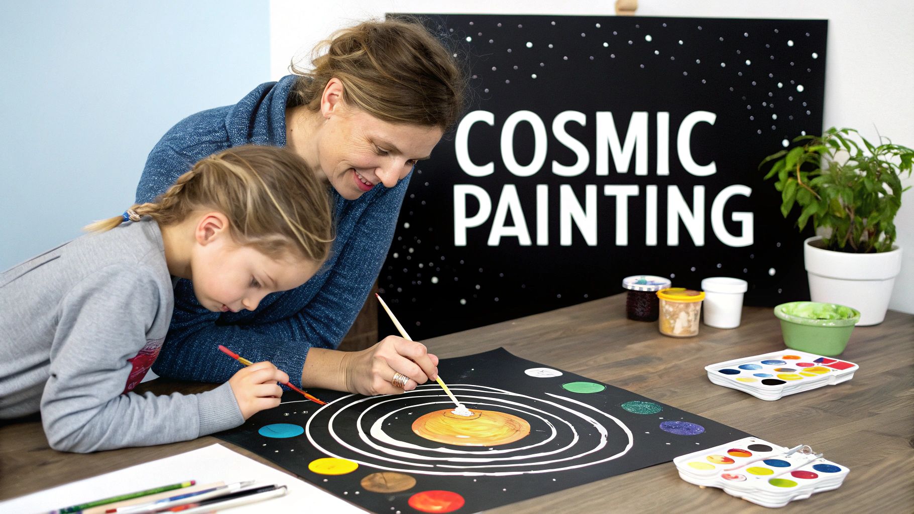 A smiling woman and a child painting a colorful solar system together on black paper.