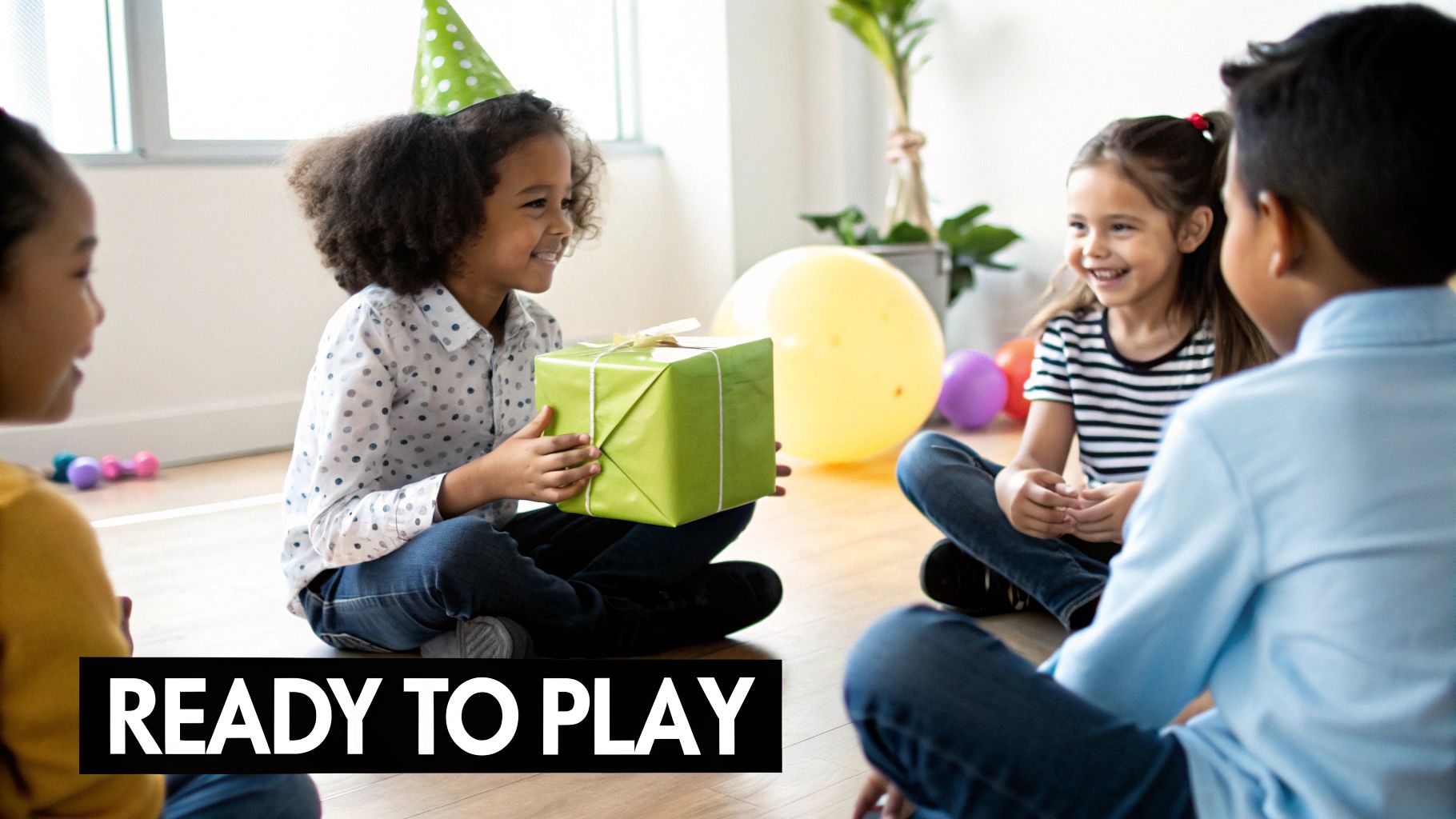 Happy kids sitting on the floor at a birthday party, one child holding a green present.