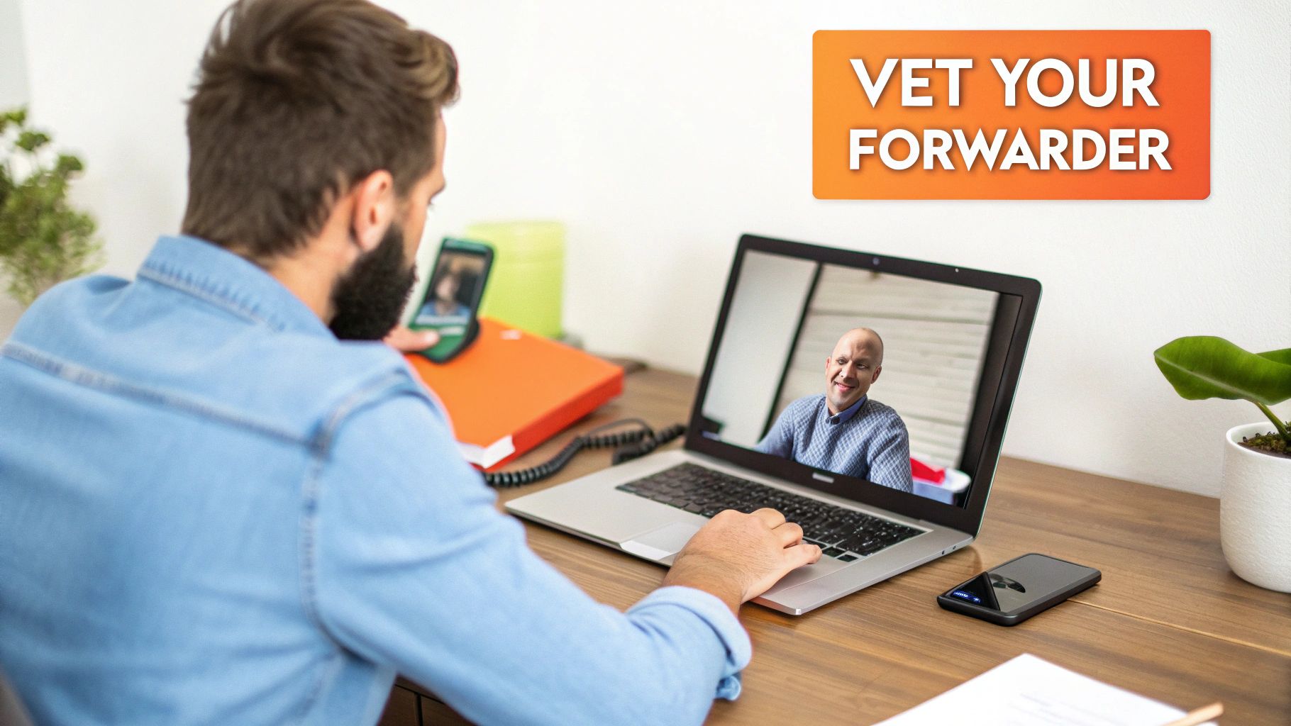 Man on a video call at a desk, vetting a forwarder on his laptop and phone.