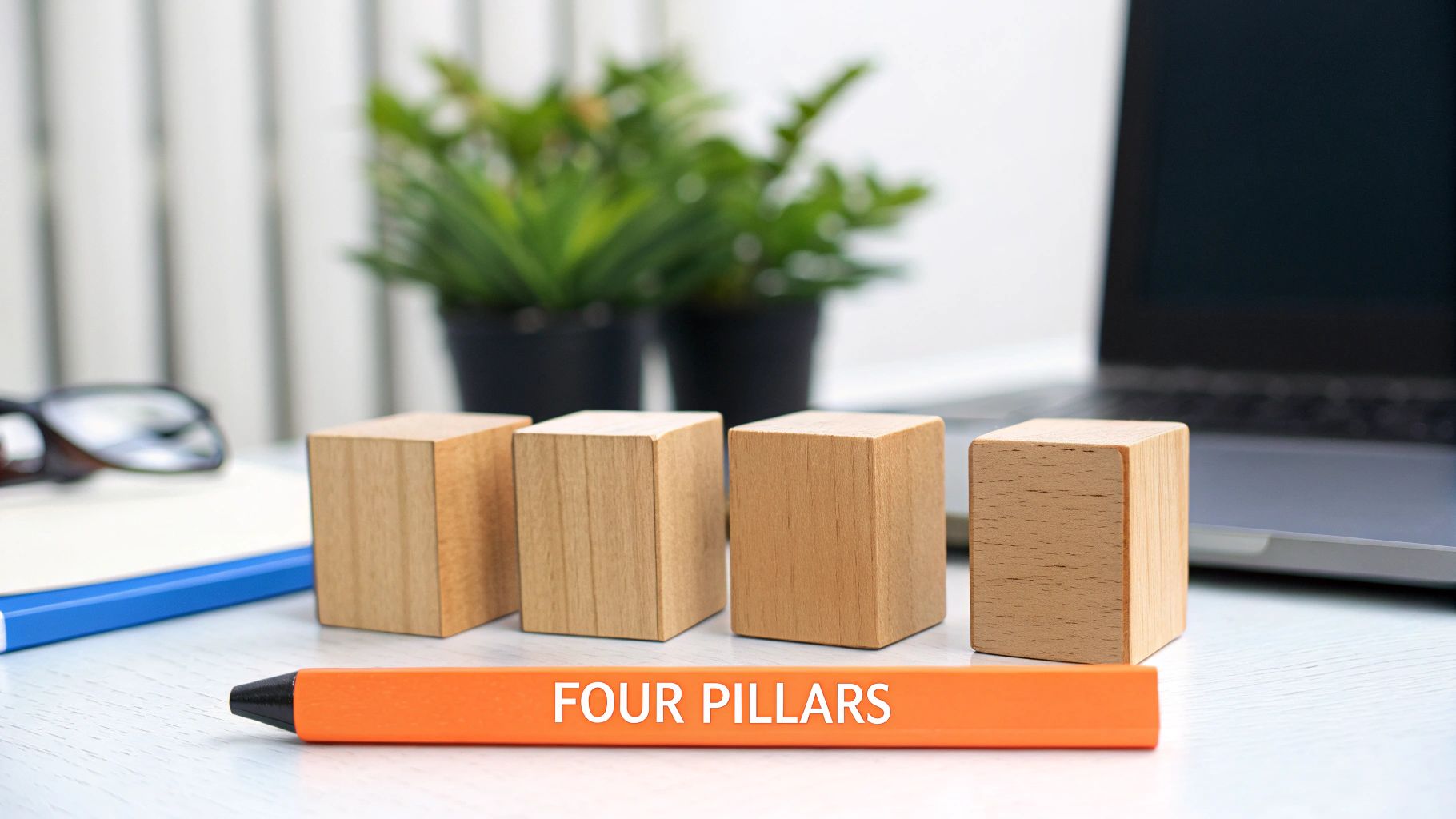 Four wooden blocks and an orange pen saying 'FOUR PILLARS' on a desk, symbolizing foundational concepts.
