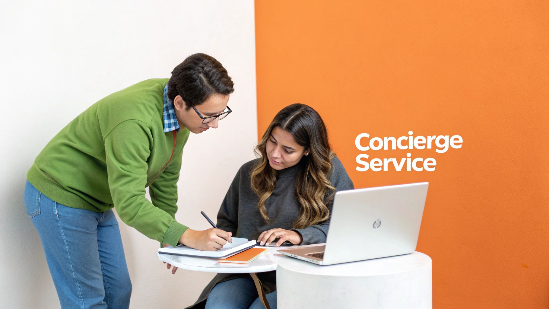 A man assists a woman writing at a table with a laptop, against a backdrop of 'Concierge Service'.