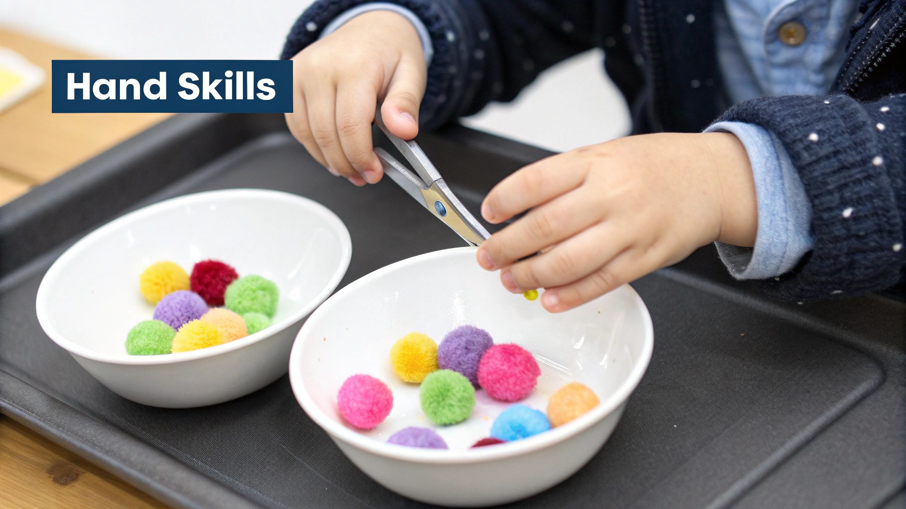 Close-up of a child's hands using tweezers to transfer colorful pom-poms between bowls, developing fine motor skills.