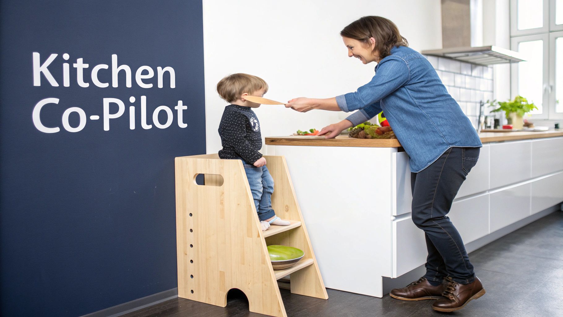 A child stands in a Montessori learning tower, happily helping in the kitchen.