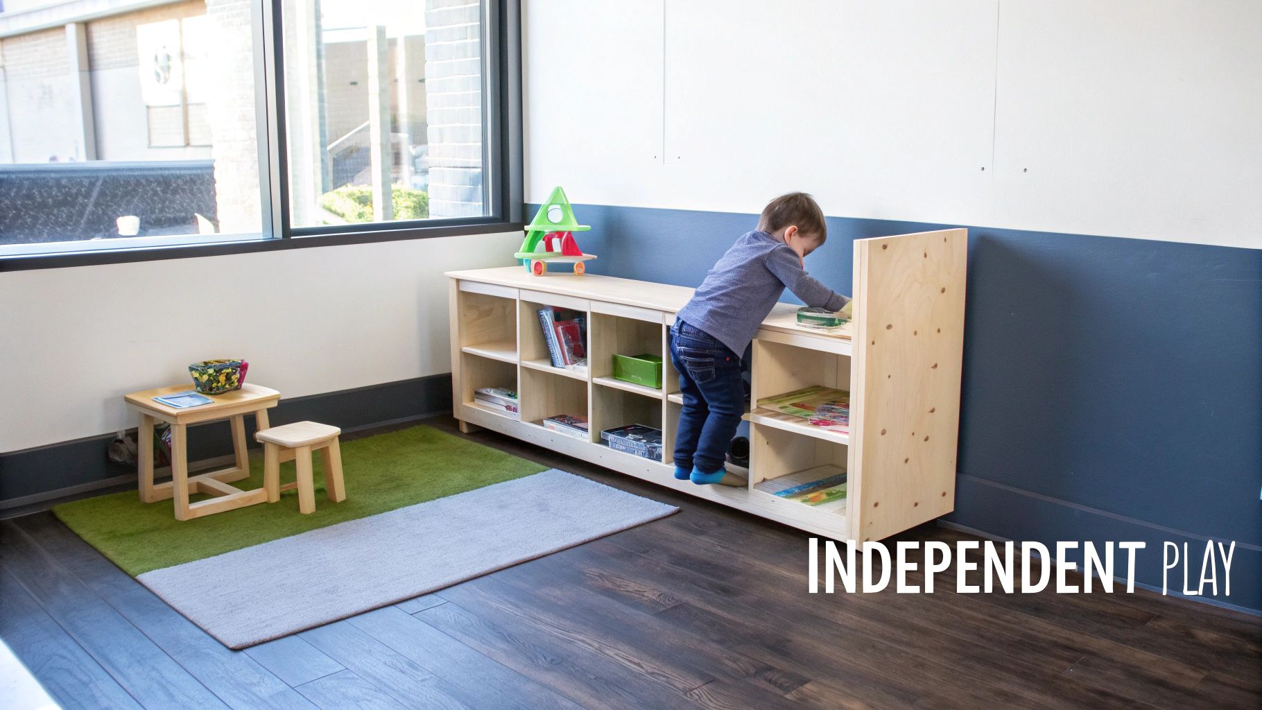A young child plays independently, climbing on a low wooden bookshelf in a bright learning room.