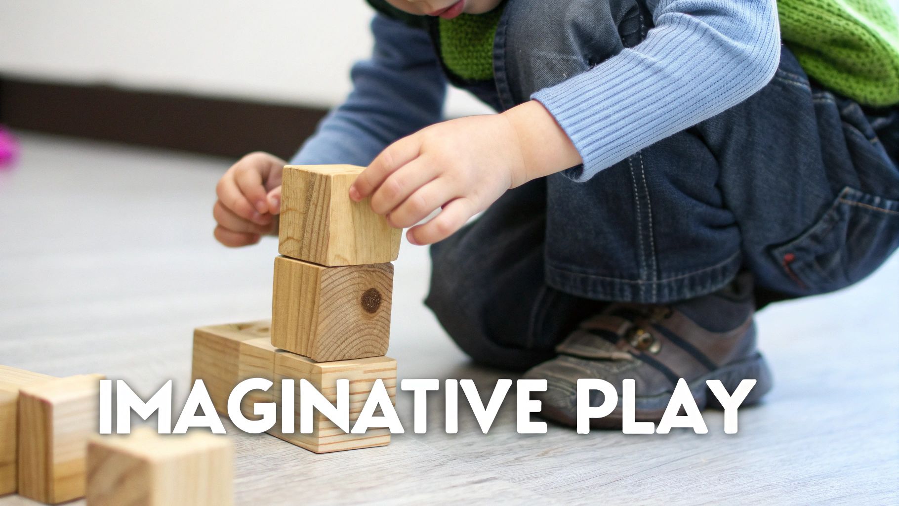 A child's hands stack natural wooden blocks on a light wooden floor, promoting imaginative play.